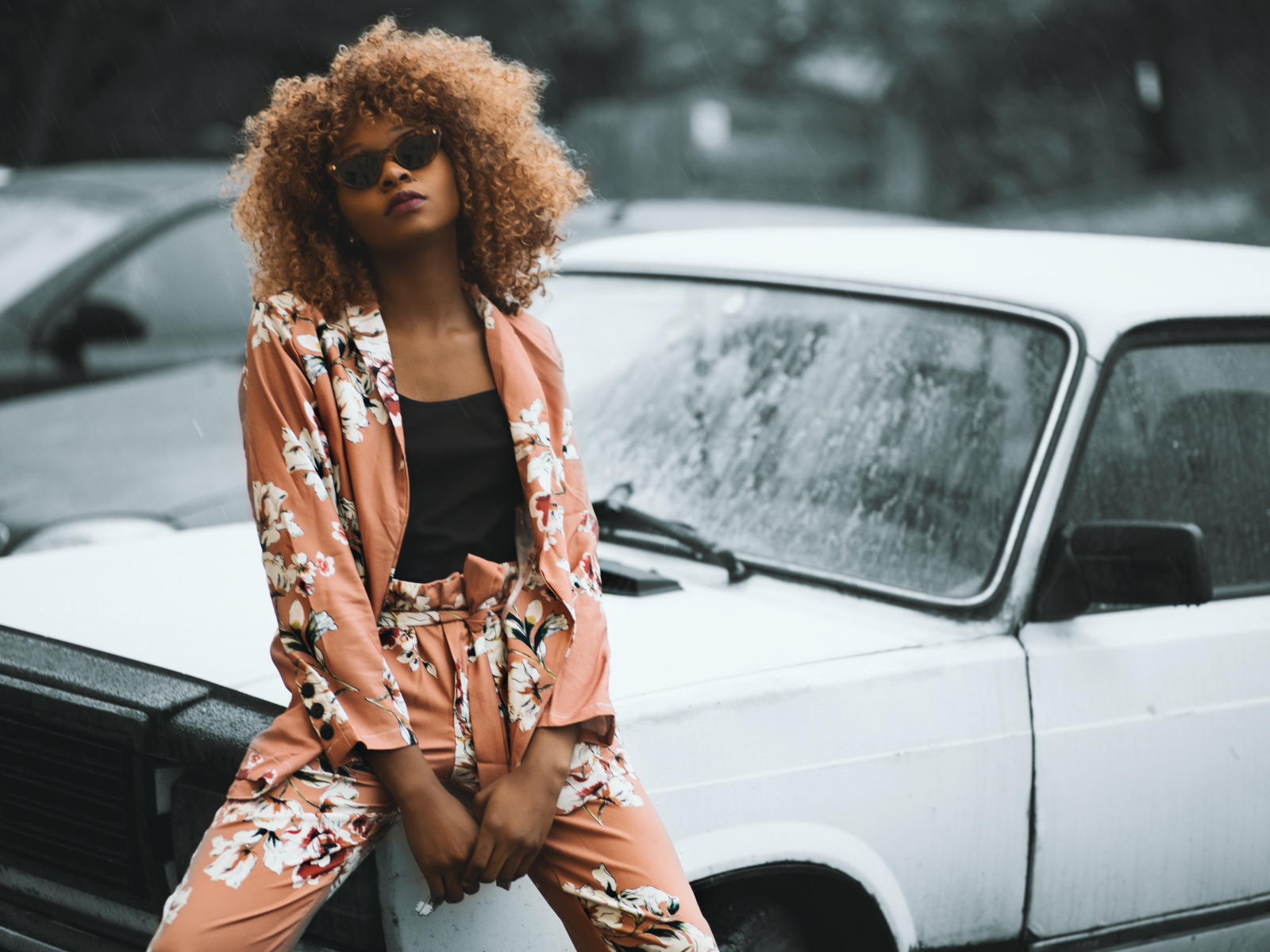 Красивая темнокожая девушка сидит на автомобиле 