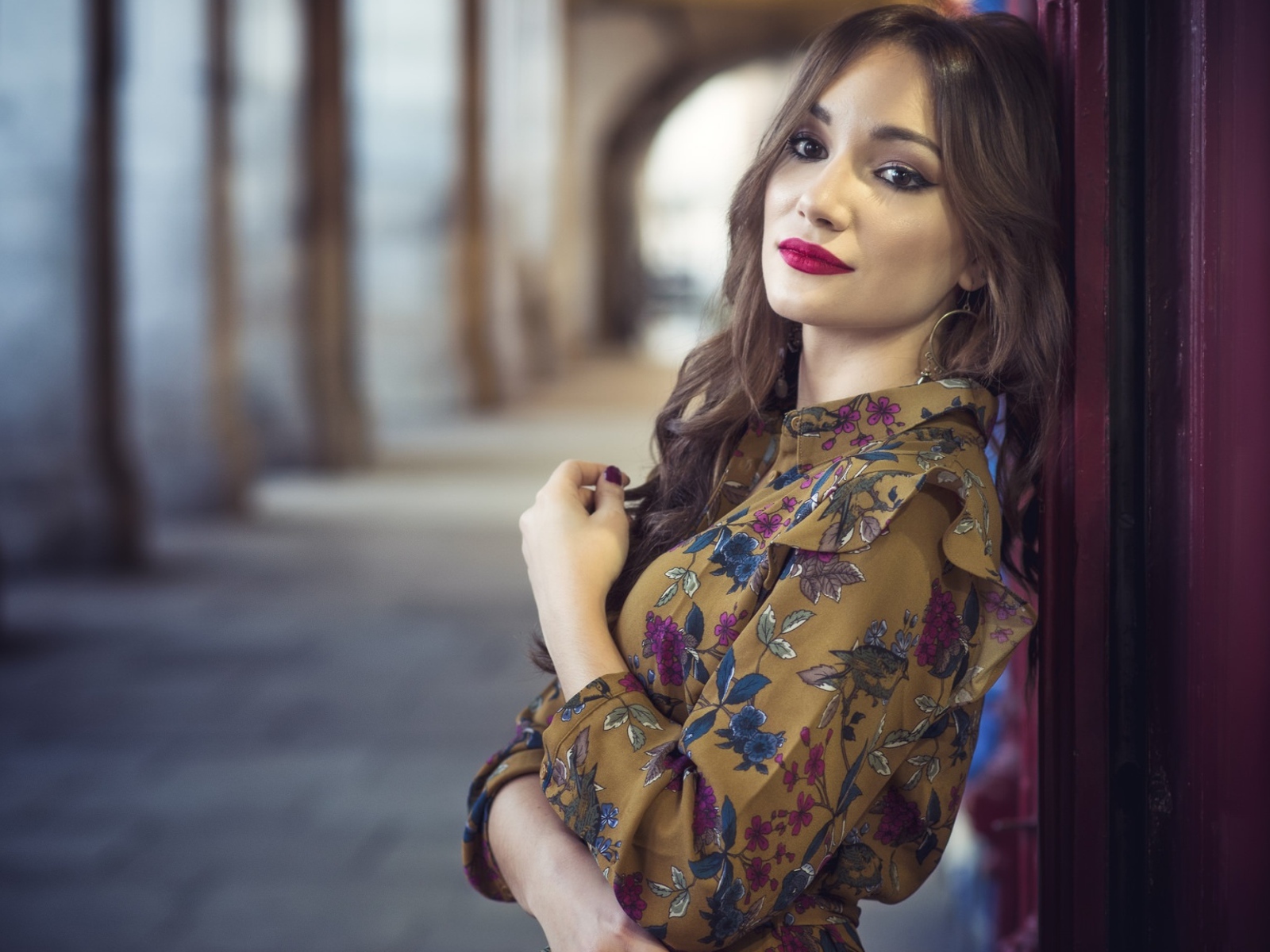 Девушка шатенка в красивом платье у стены