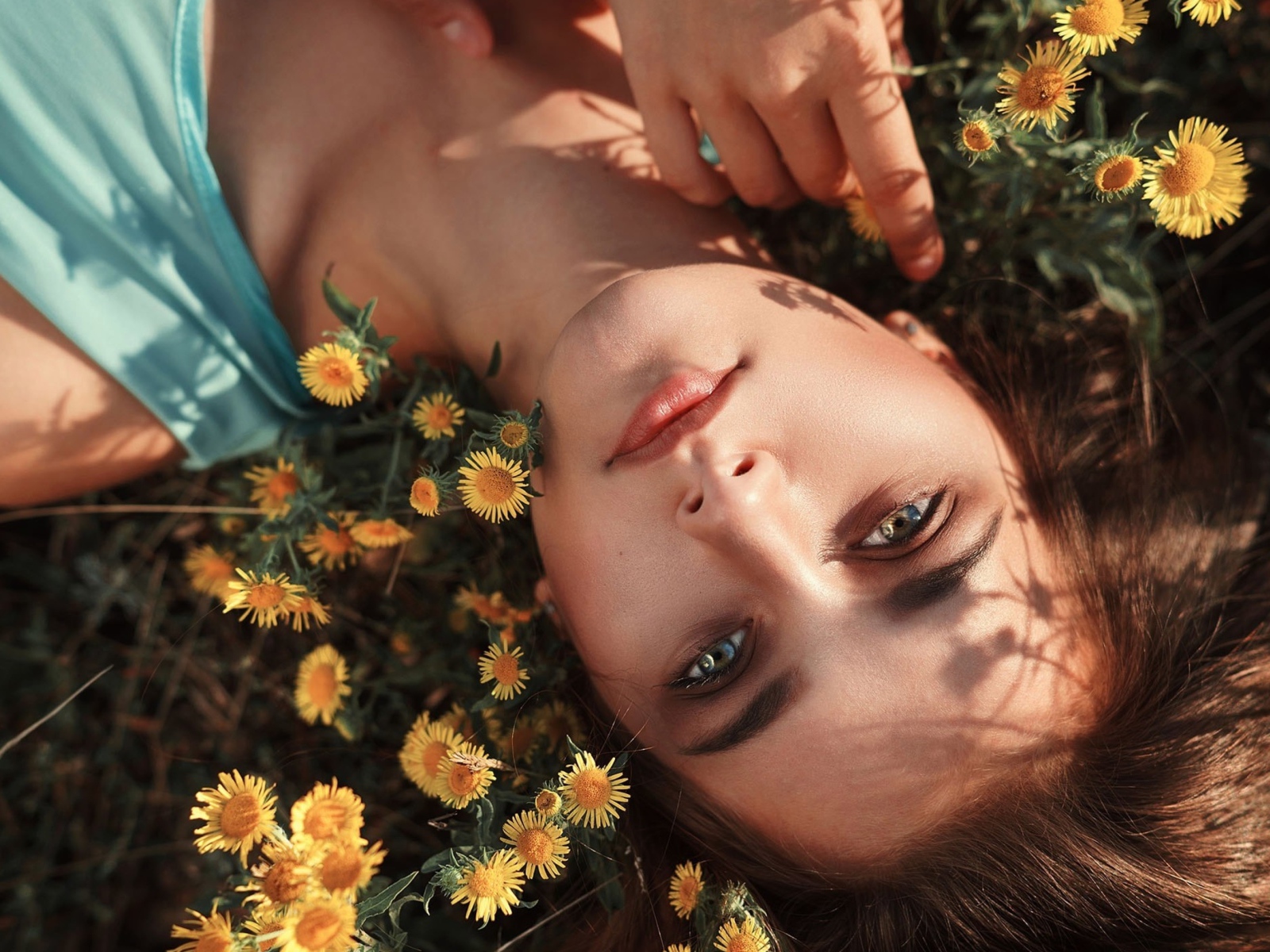 Красивая шатенка лежит на земле с желтыми цветами