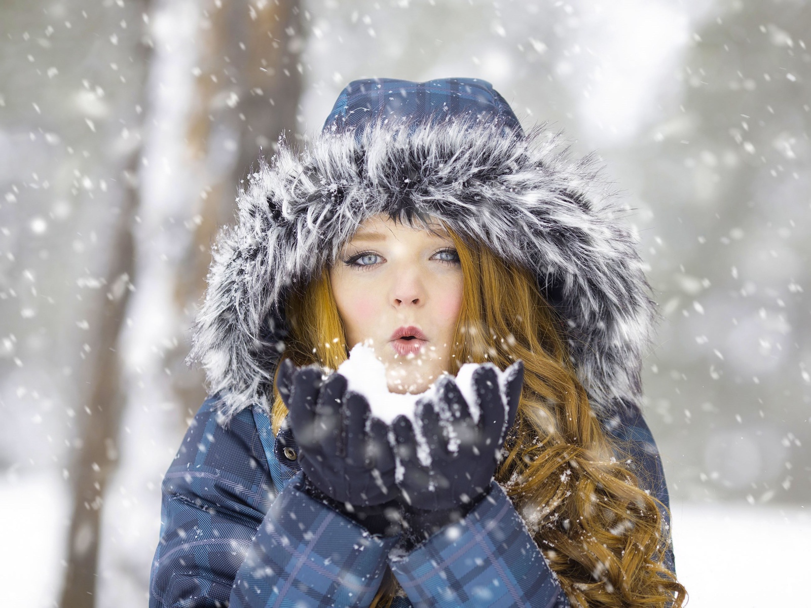 Красивая девушка в теплой куртке со снегом в руках