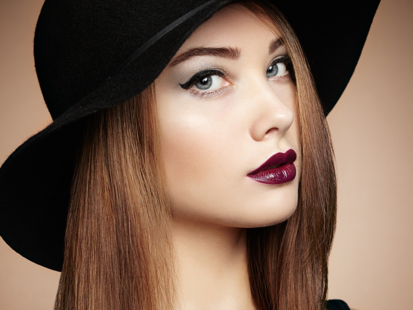 Красивая девушка с ярким макияжем в большой черной шляпе