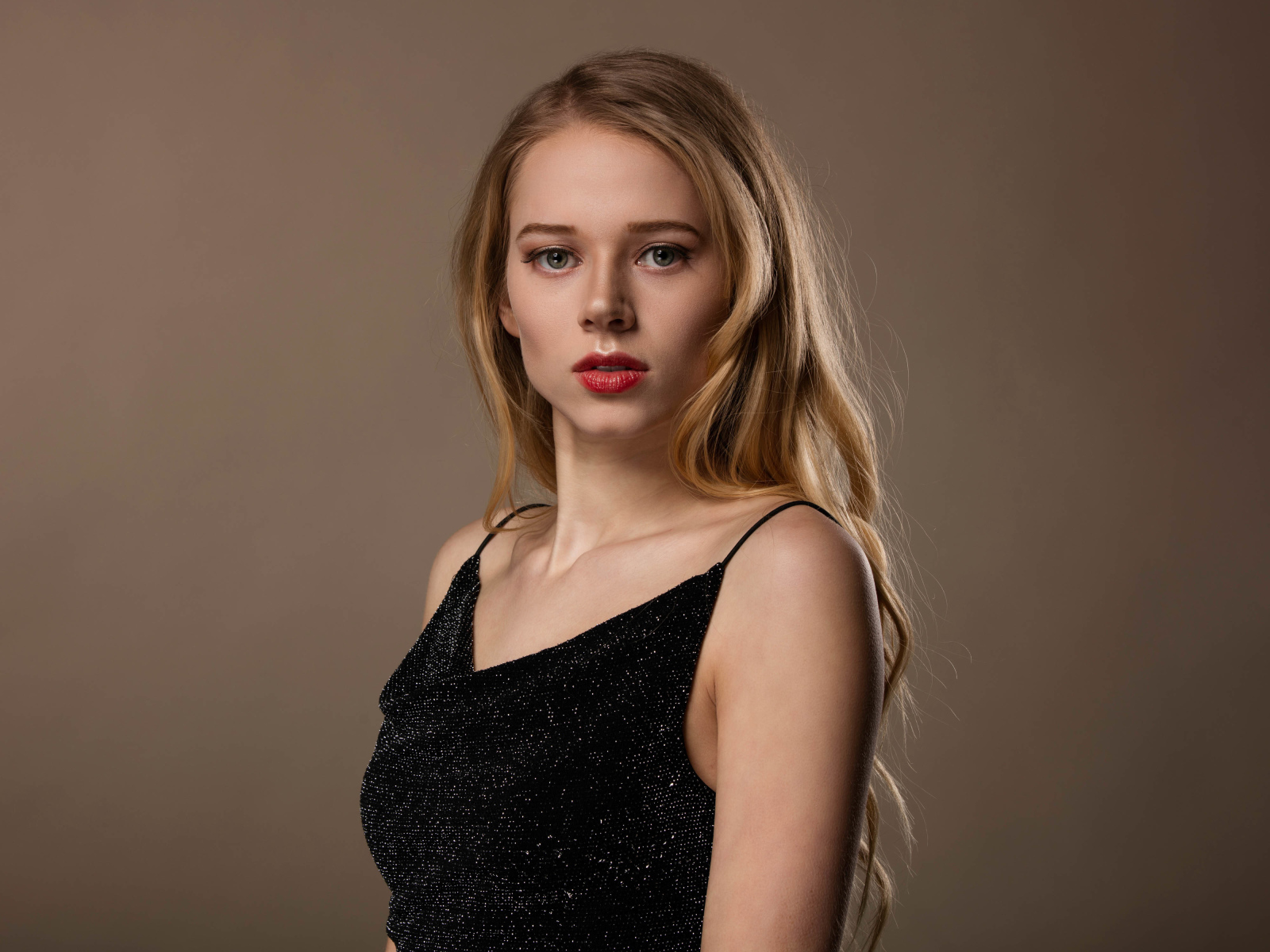 Нежная девушка модель в черном платье на сером фоне