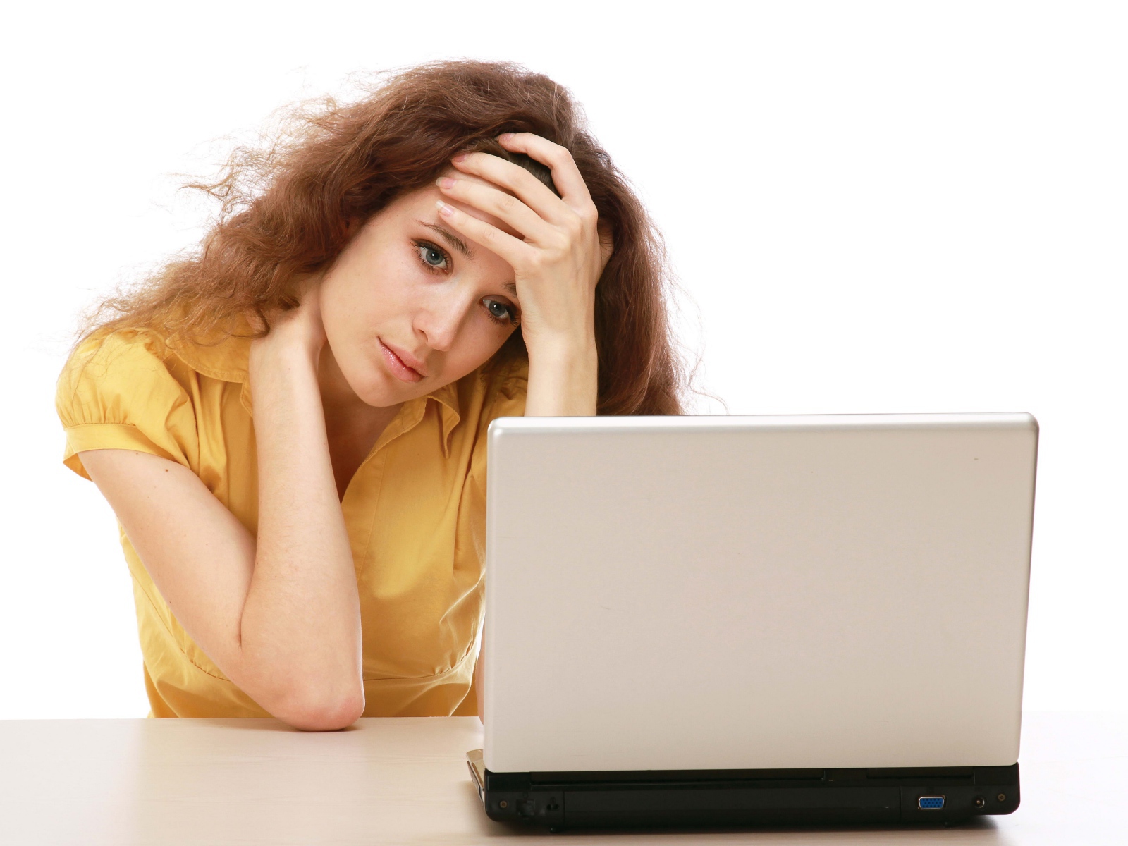 Грустная девушка сидит возле ноутбука 