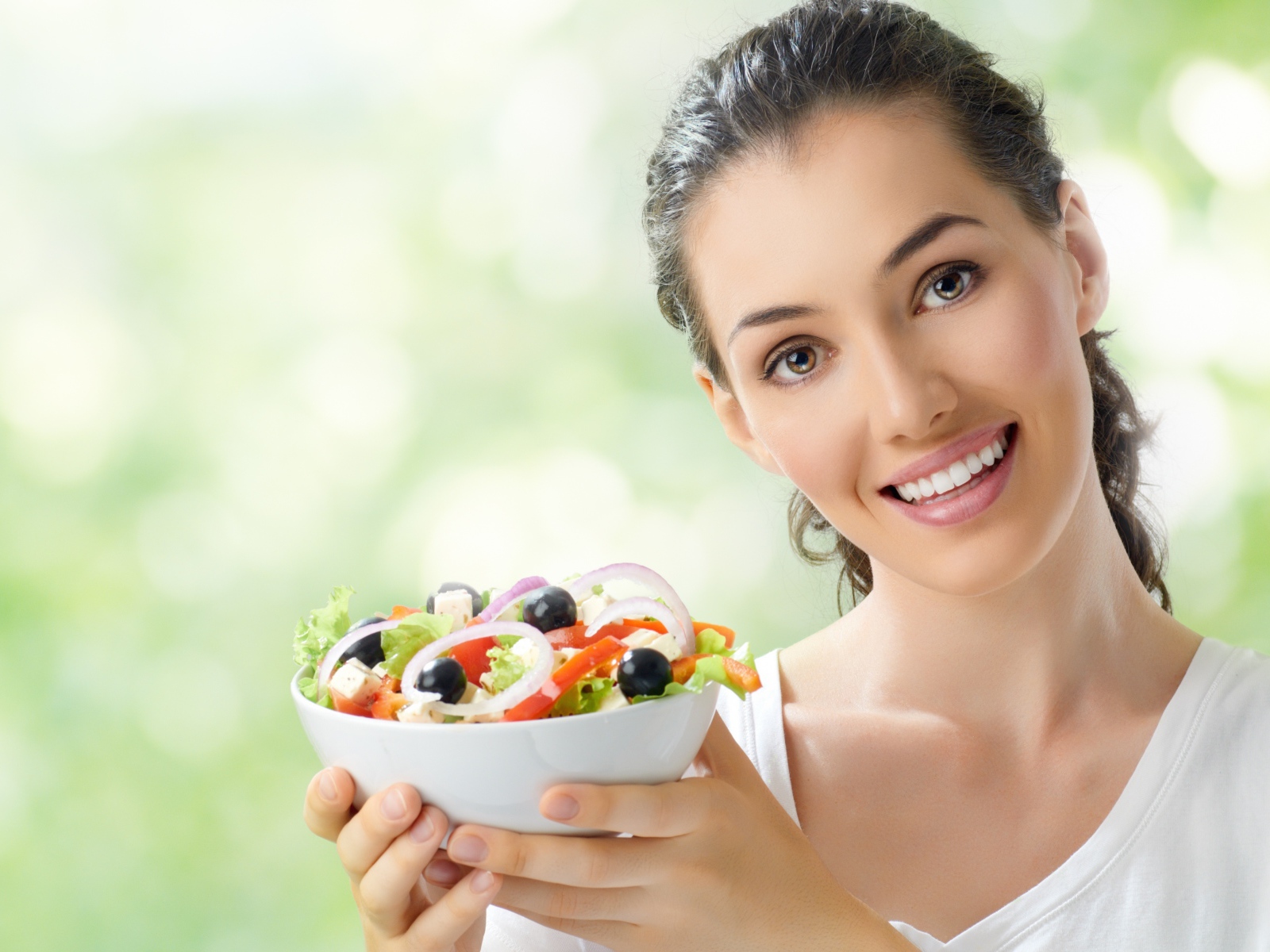Улыбающаяся девушка с тарелкой овощного салата