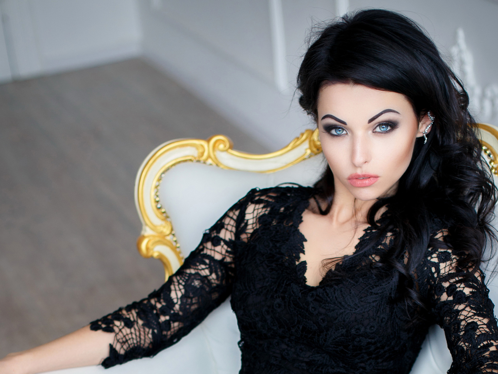 Эффектная брюнетка в черном платье сидит в кресле