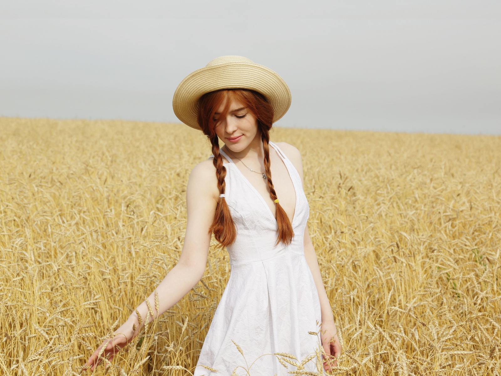 Молодая девушка в белом платье на поле с пшеницей