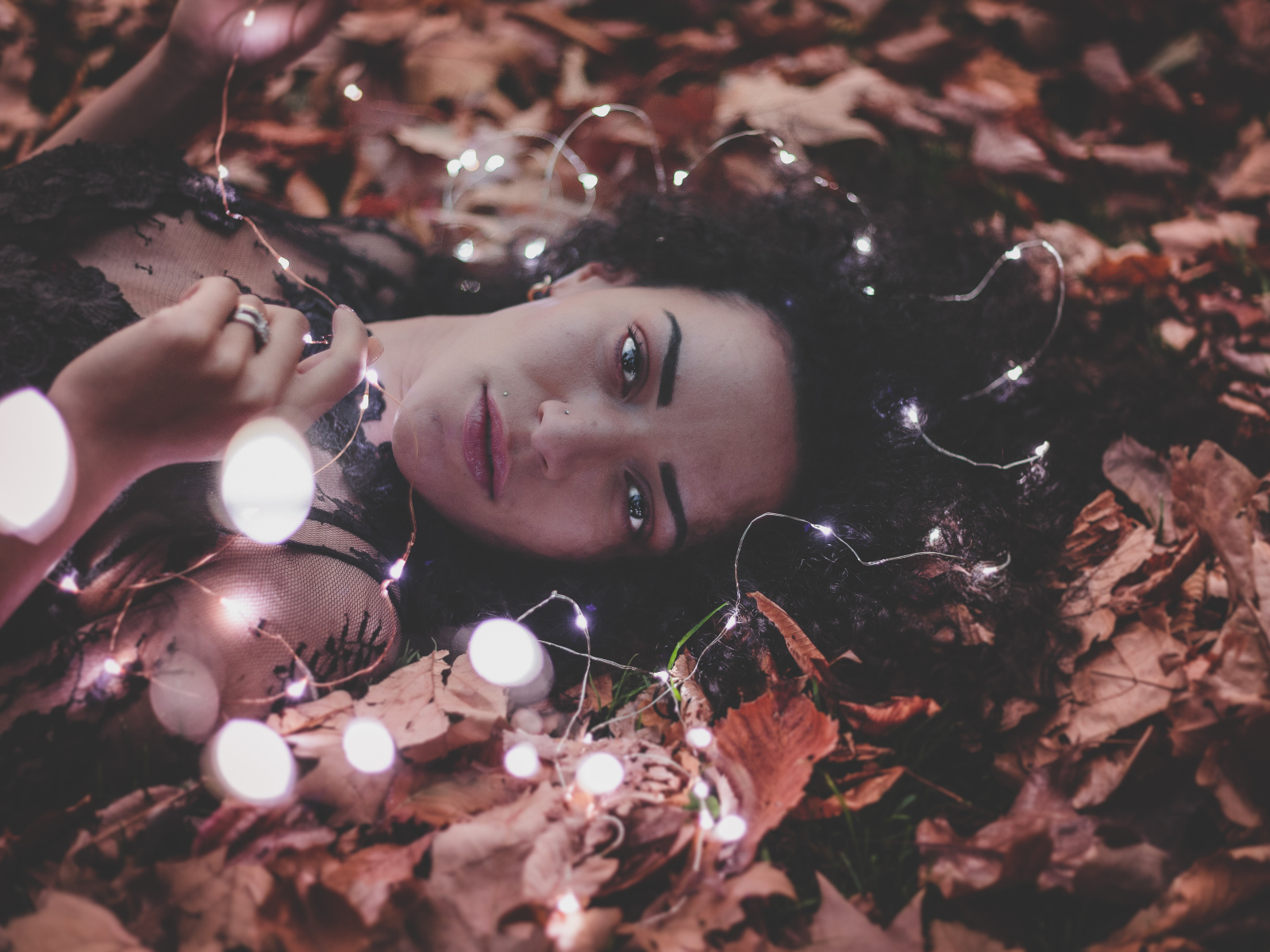 Молодая девушка лежит с гирляндой на желтых листьях