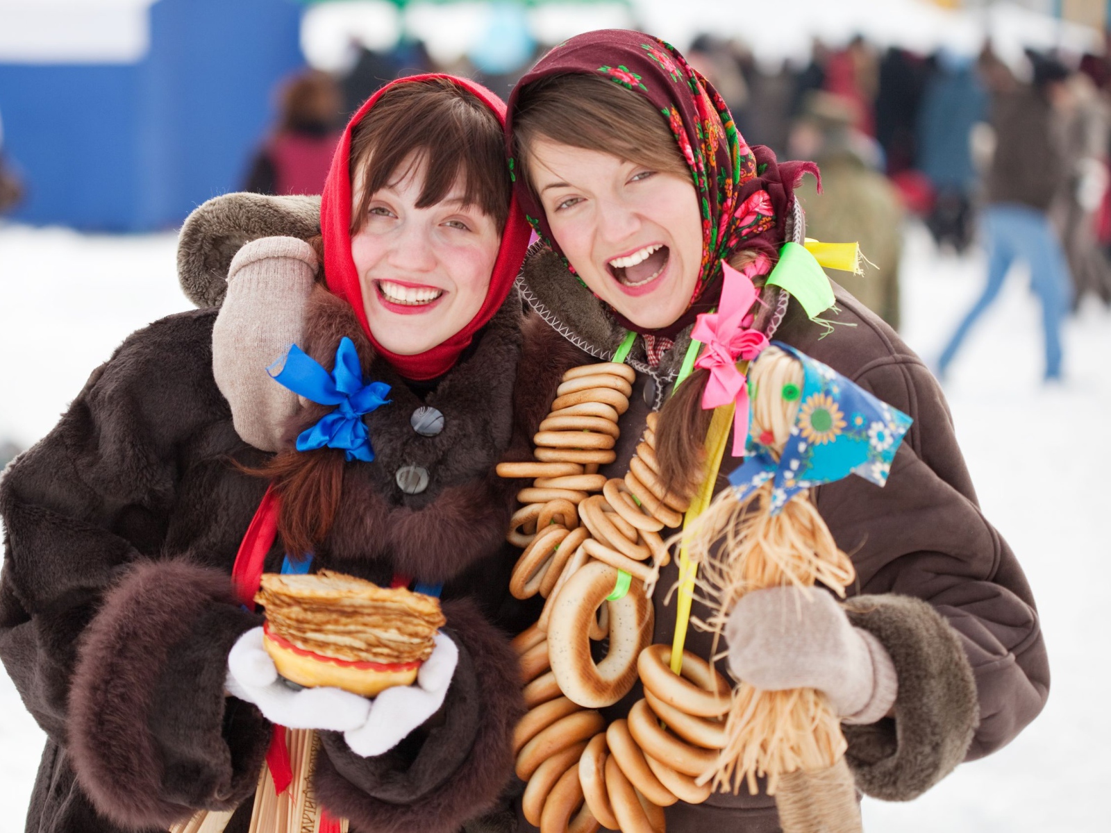 Two girls with pancakes and donuts at Shrovetide