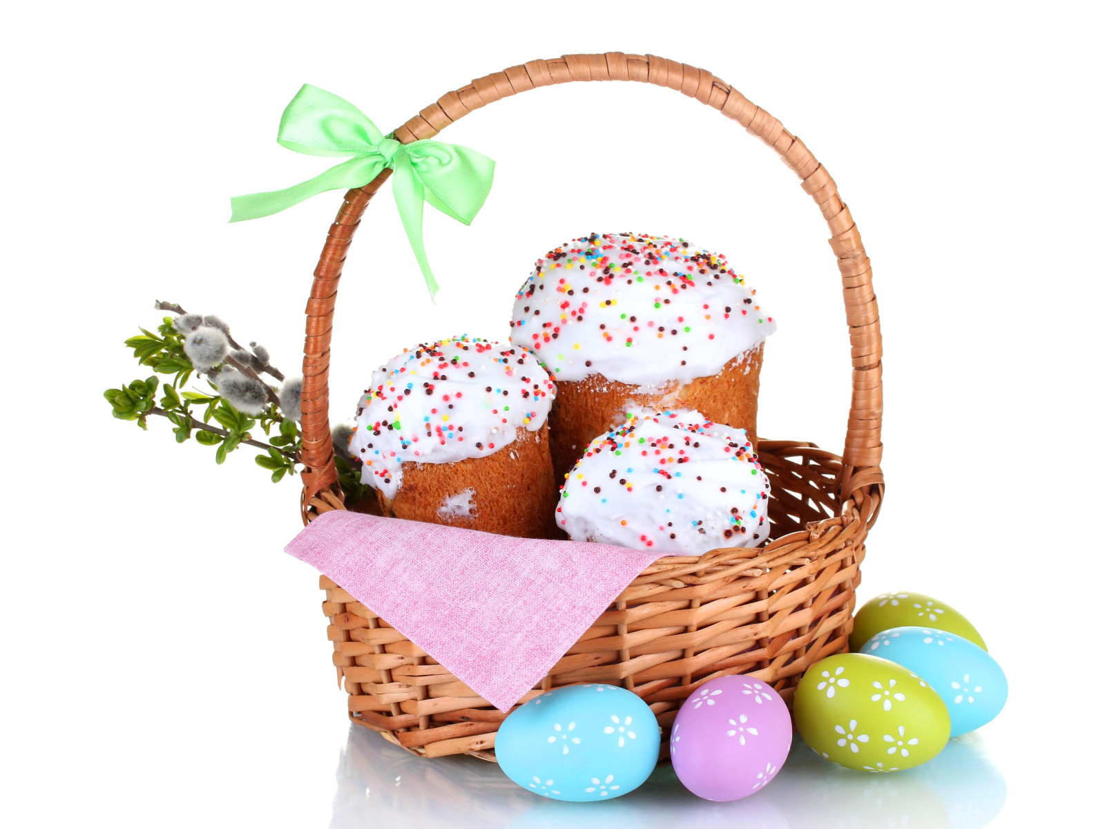 Пасхальные куличи в корзине с крашеными яйцами на белом фоне