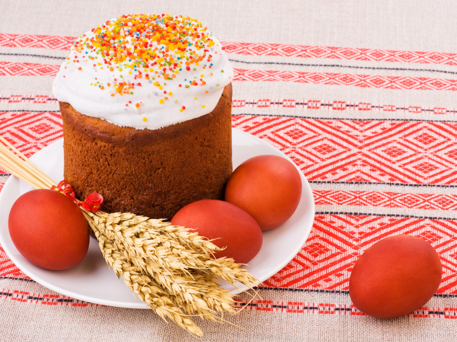 Пасха с крашеными яйцами и колосьями пшеницы на столе с красивой скатертью