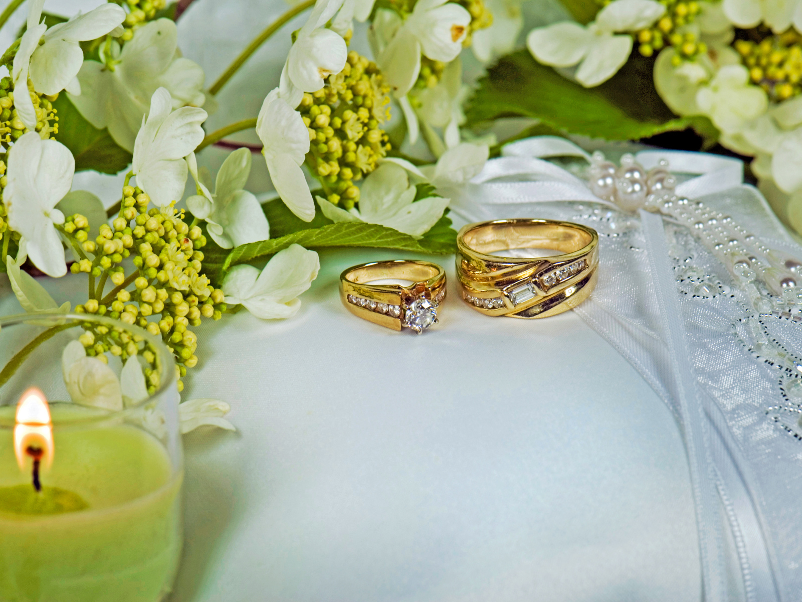 Two wedding rings on a pillow trimmed with flowers