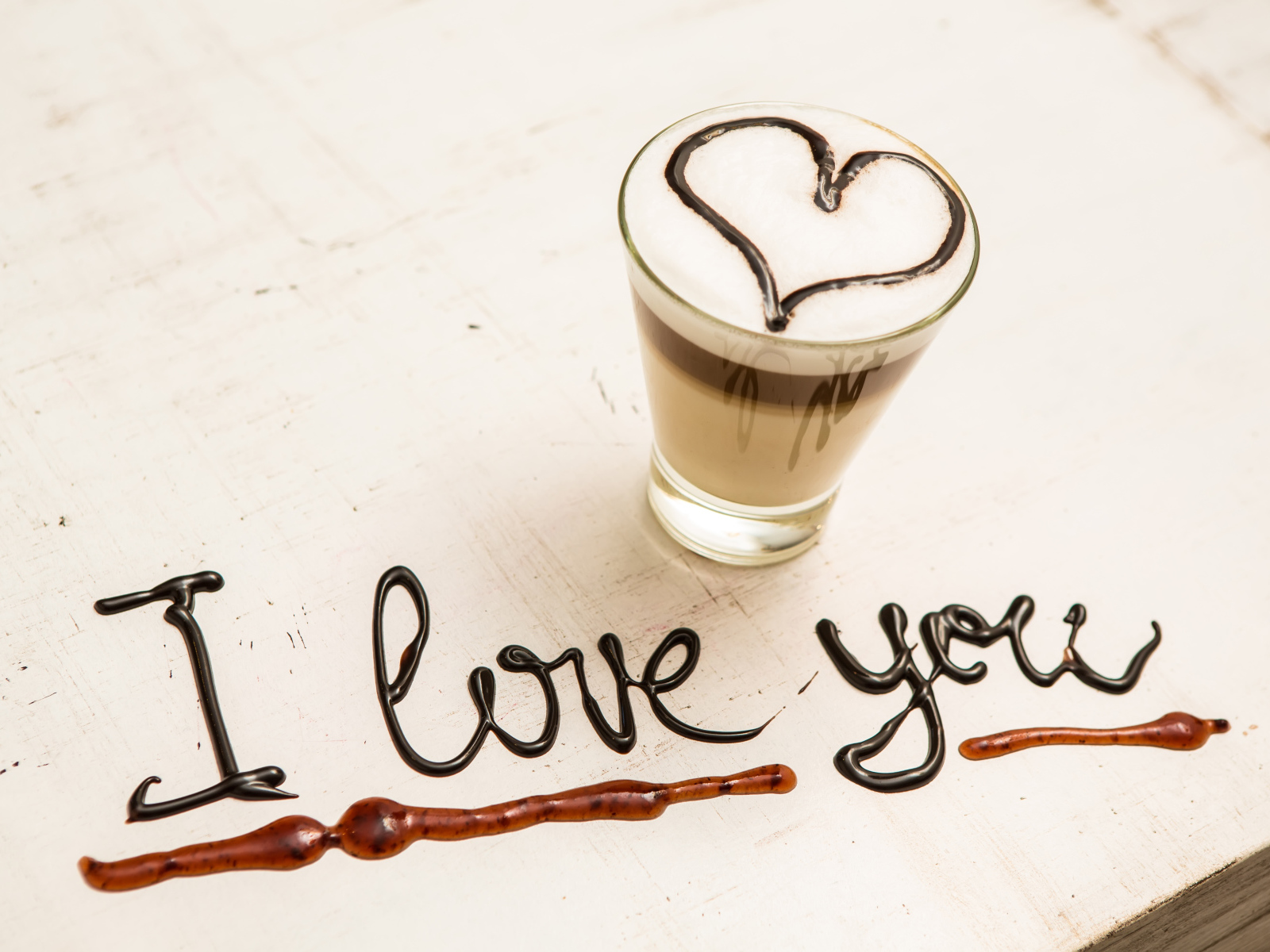 Стакан кофе с сердцем и надпись шоколадом Я тебя люблю  на столе