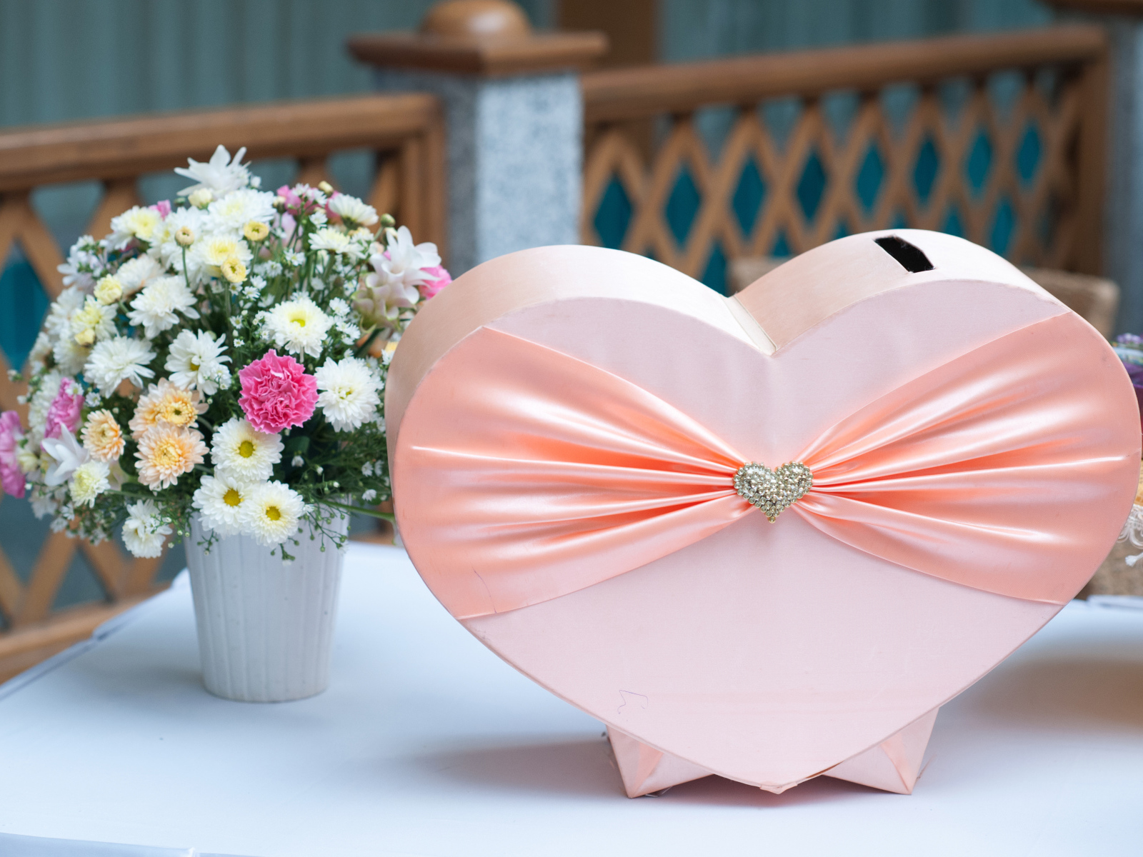 Большая розовая коробка в форме сердца на столе с букетом хризантем