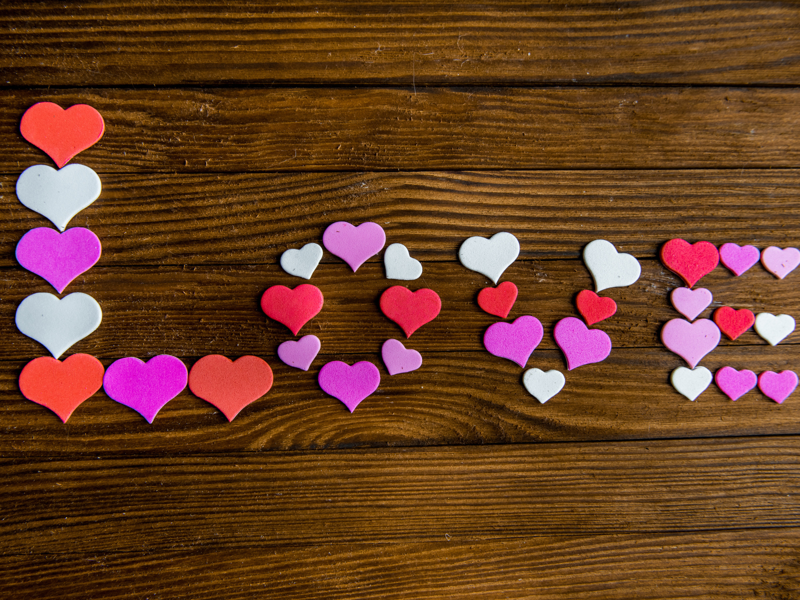 Надпись любовь из разноцветных сердец на деревянном столе