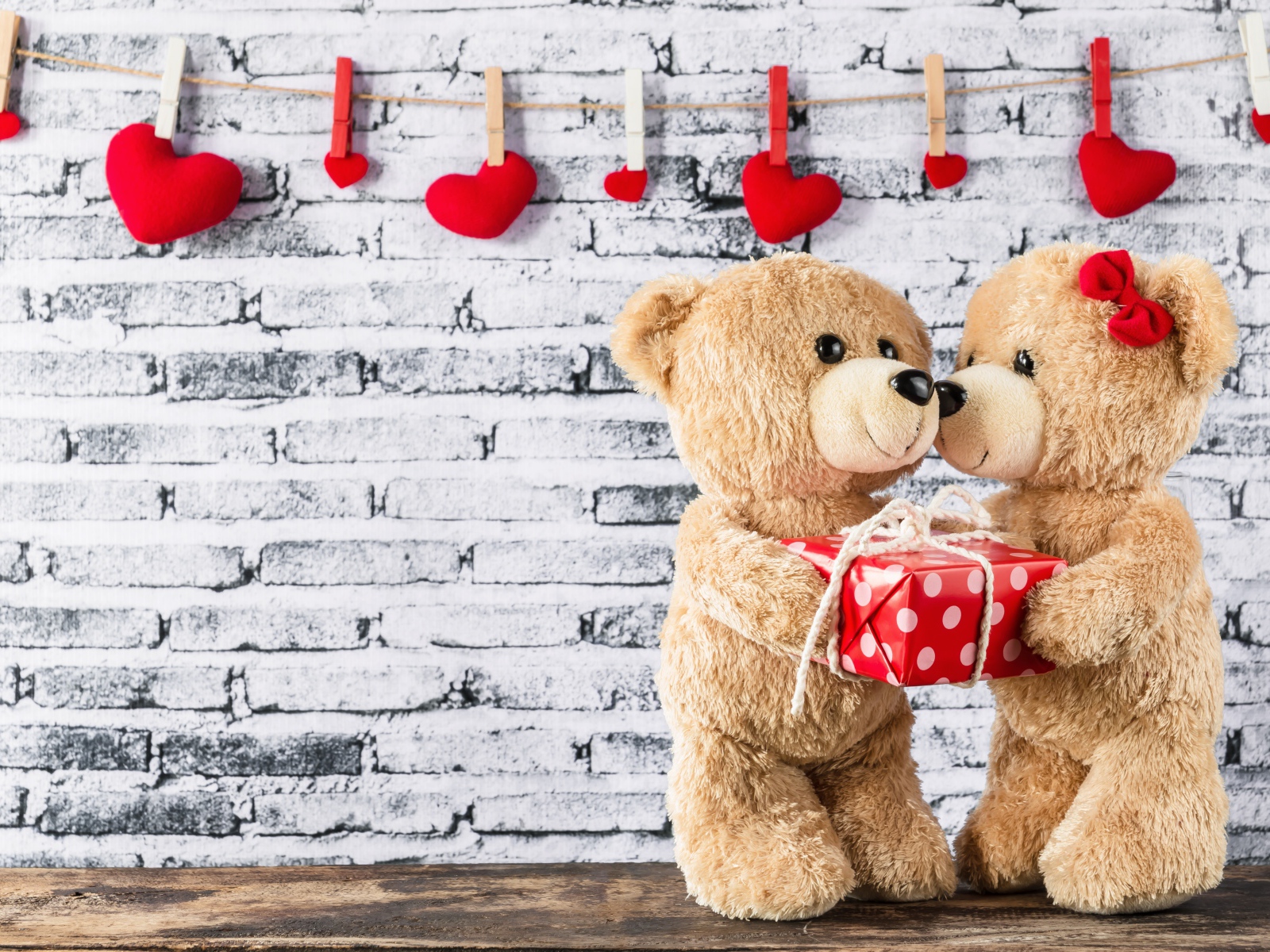 Влюбленные плюшевые мишки на фоне стены с сердечками 