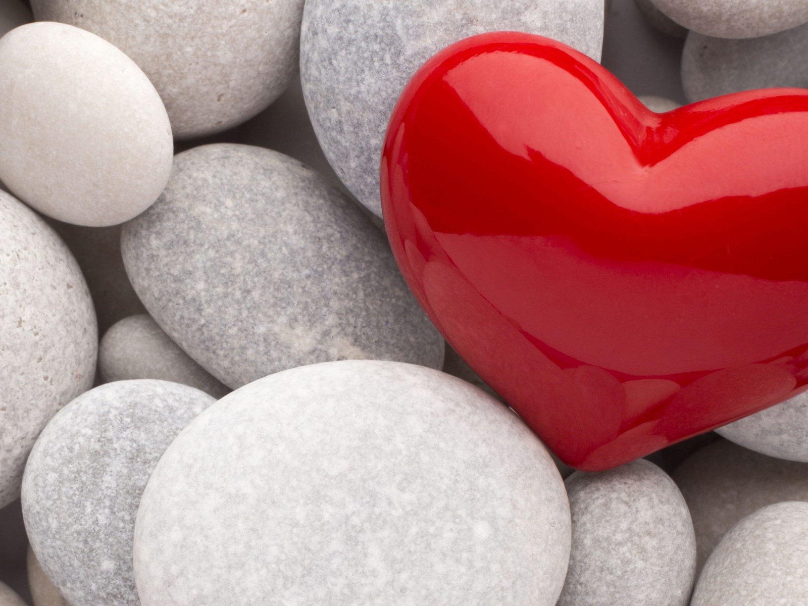Красное сердце лежит на серых камнях 