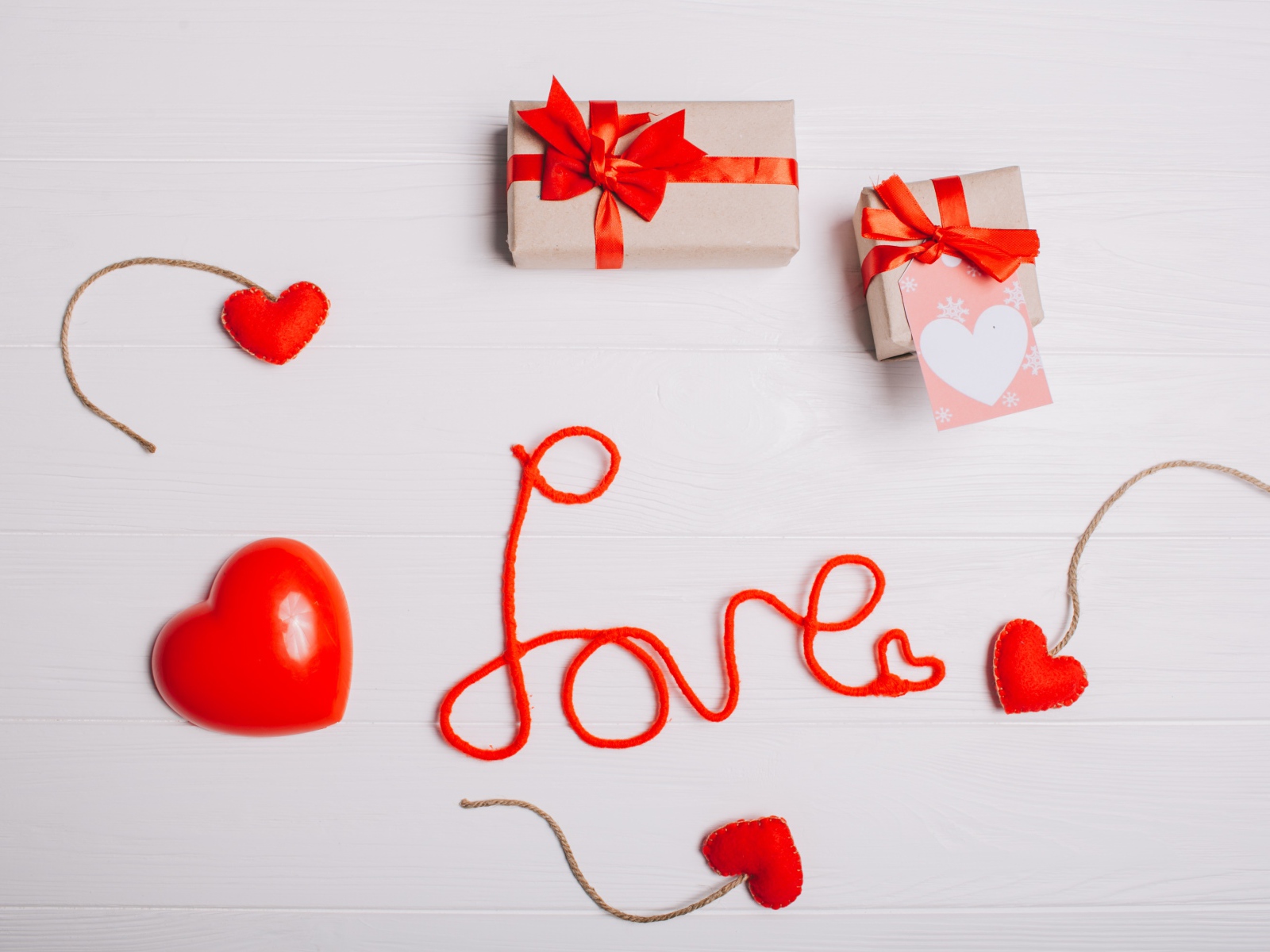 Надпись любовь красными нитями на сером фоне с сердечками и подарками
