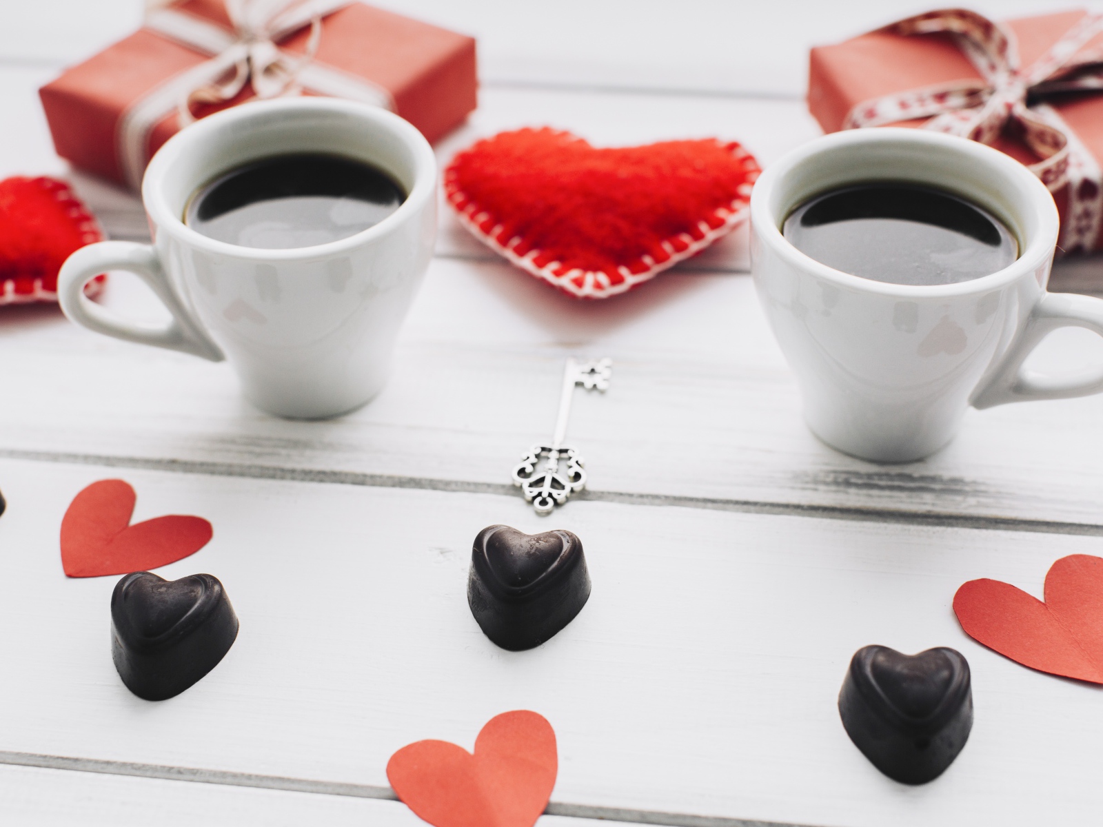 Две чашки кофе на столе с подарками, конфетами и сердечками