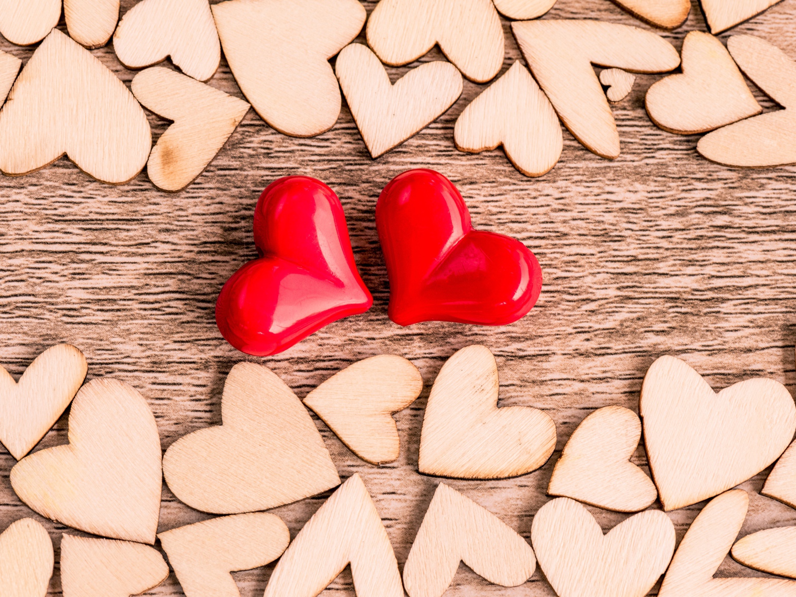 Два красных сердечка на столе с деревянными сердечками