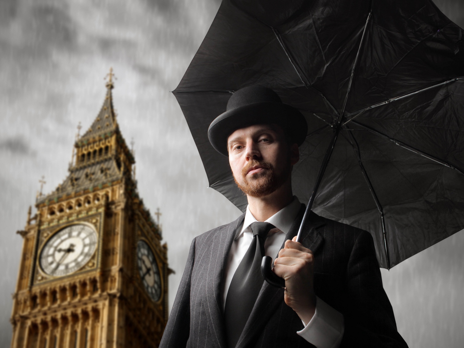 A man in a suit with a black umbrella at the tower with a clock