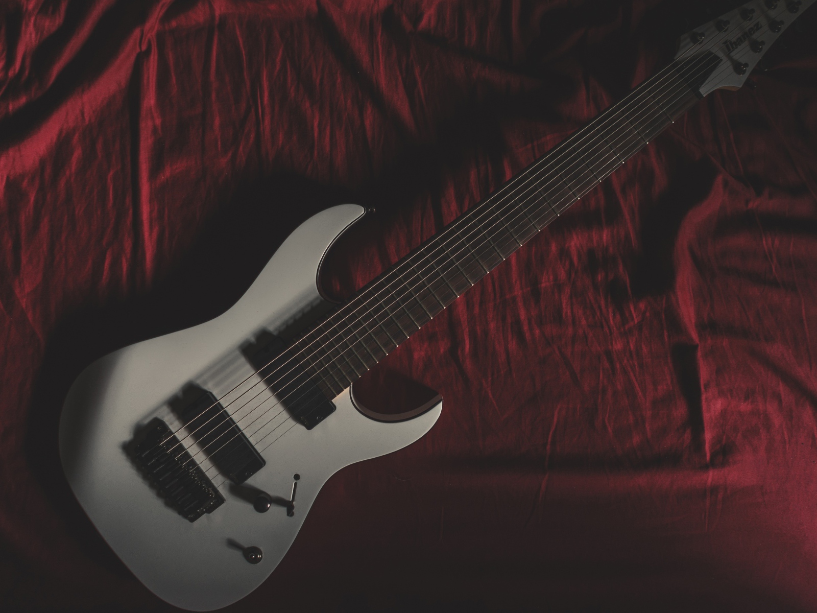 Гитара лежит на красном покрывале