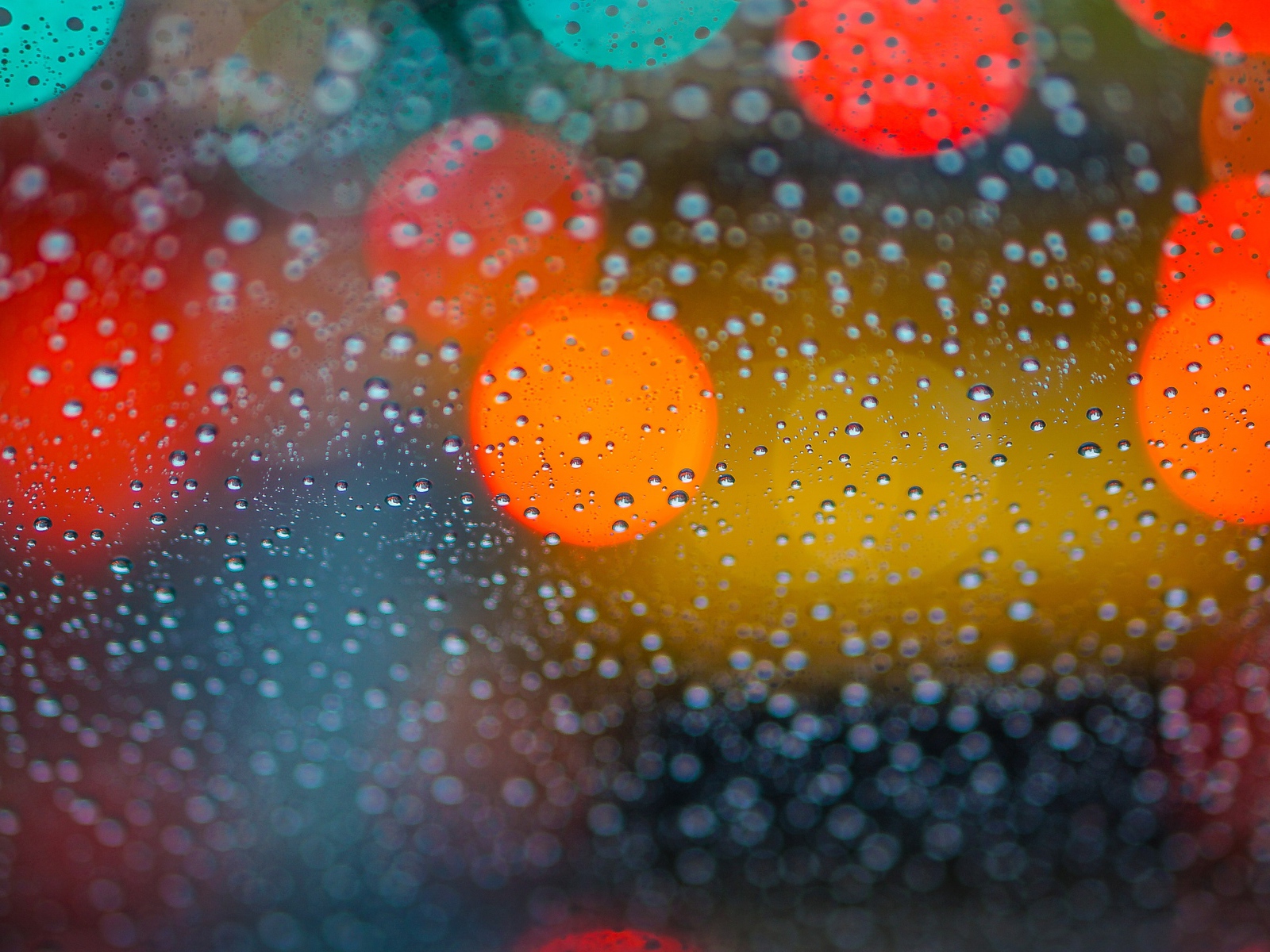 Капли дождя на стекле с разноцветными бликами