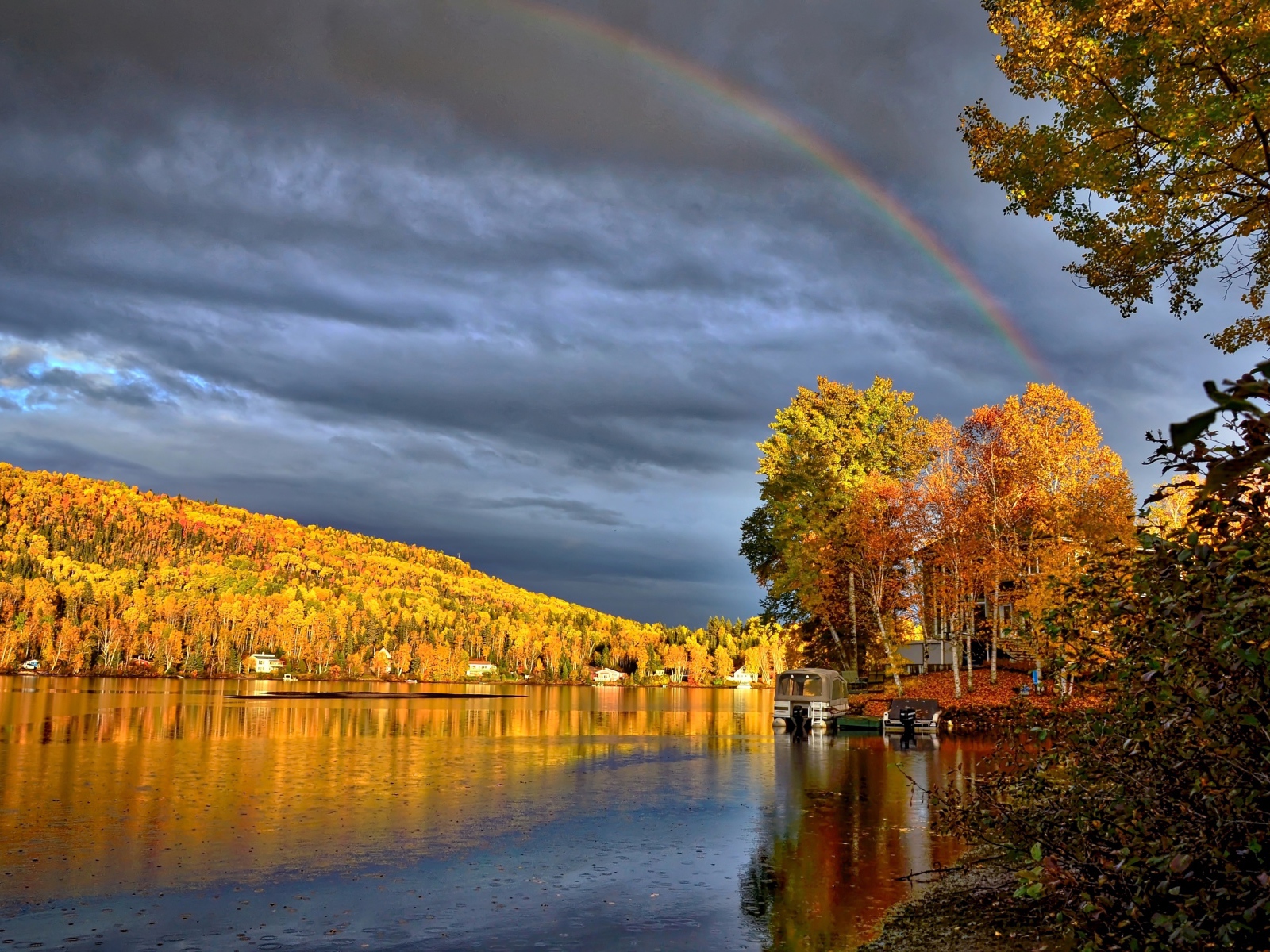 Радуга в пасмурном небе над озером у осеннего леса