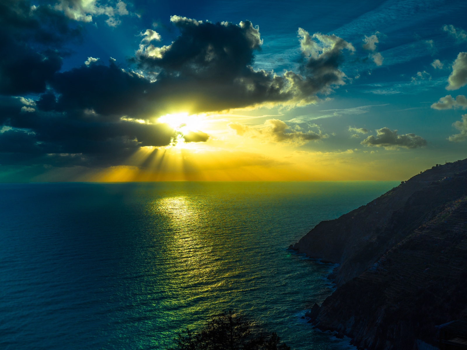 Rays of bright sun make their way through the clouds above the sea