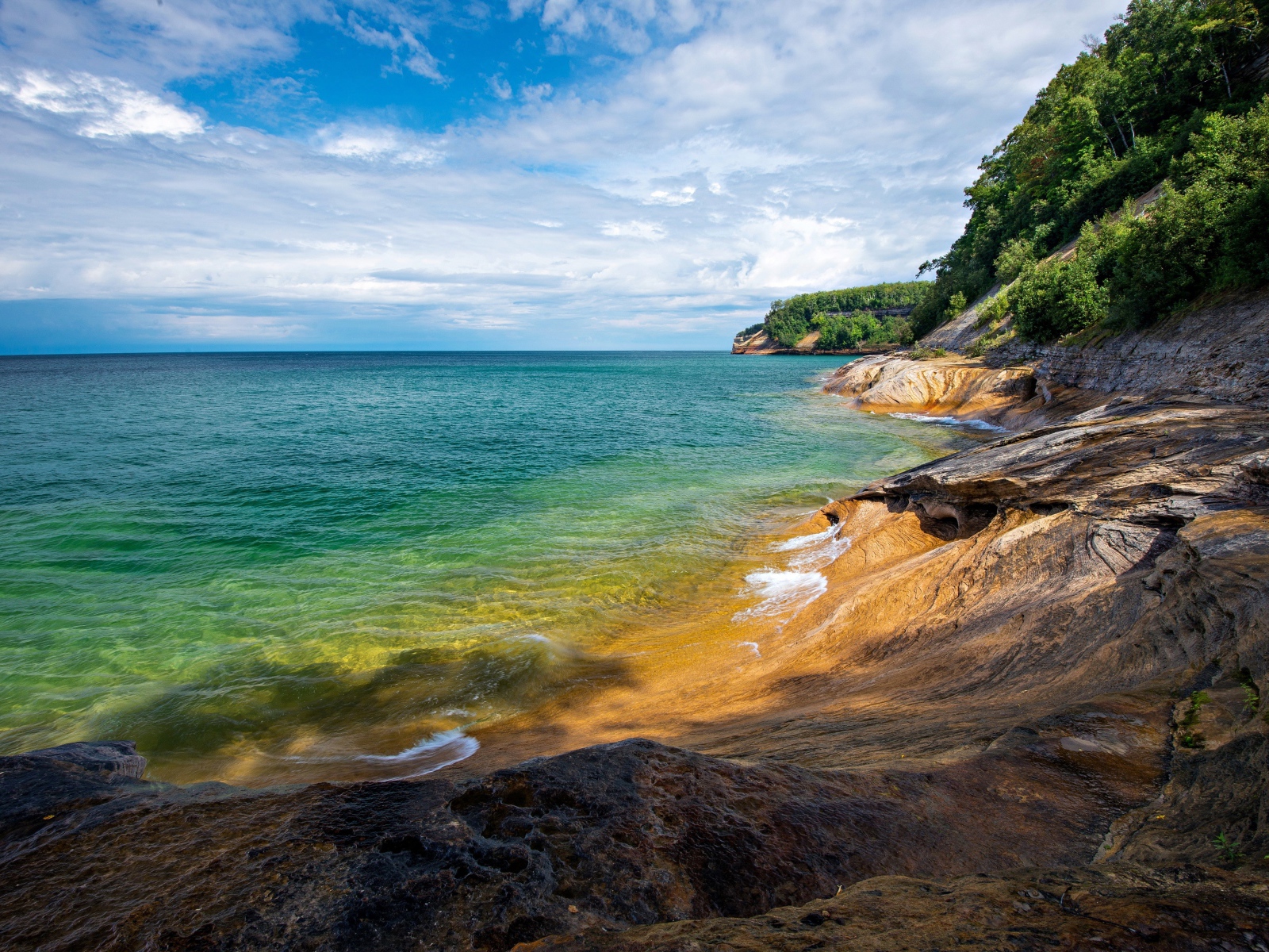 Скалистый берег у голубой воды моря на фоне неба