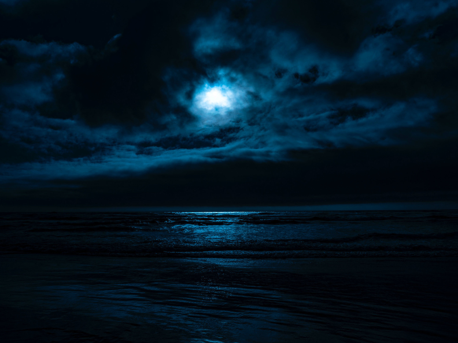 Луна в облачном небе над морем ночью