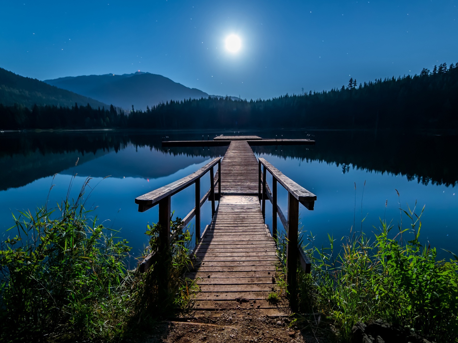 Деревянный мост на озере в полнолуние