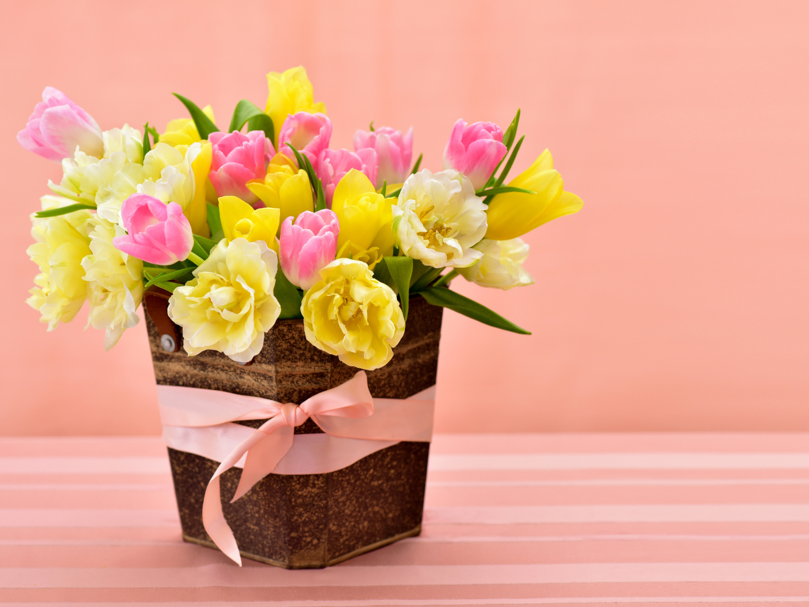 Букет красивых разноцветных тюльпанов в вазе на розовом фоне