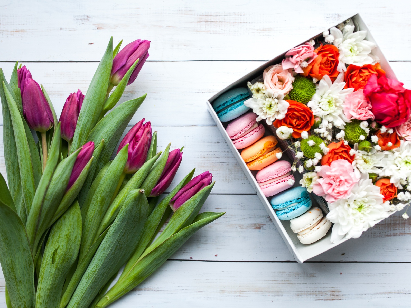 Букет сиреневых тюльпанов на столе с коробкой с макарунами