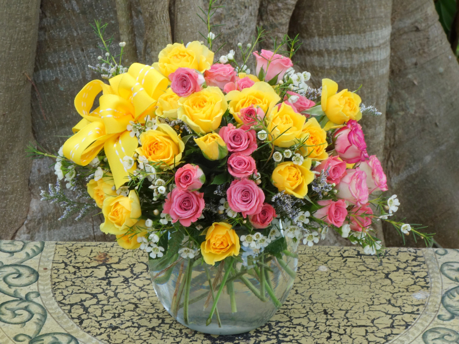 Букет желтых и розовых роз в стеклянной вазе