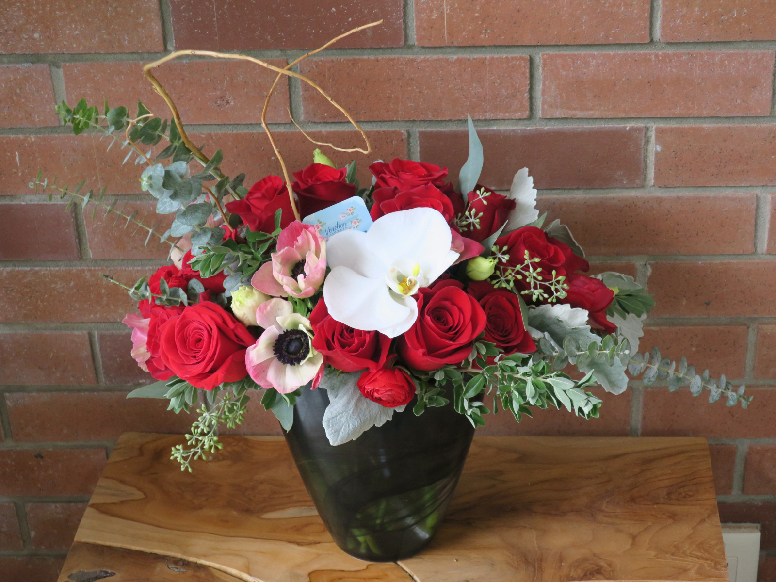 Букет с цветами анемоны, розы и орхидеи у стены 