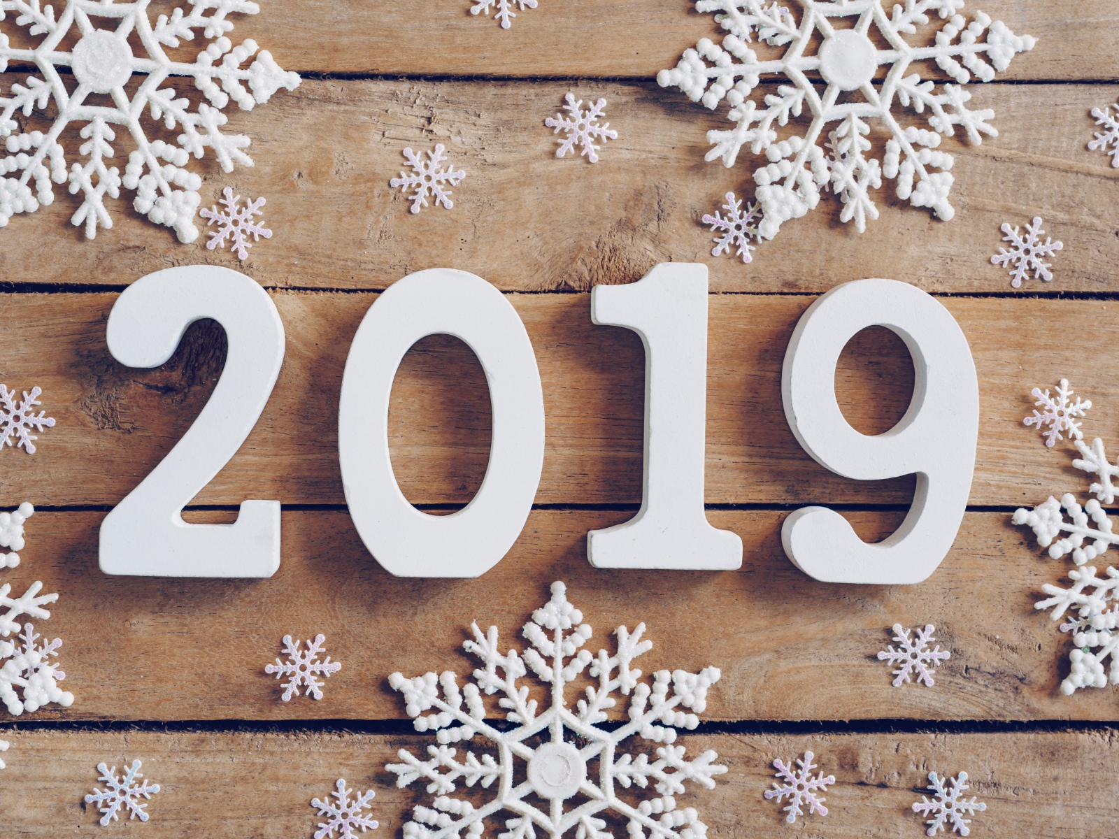 Белые цифры 2019 на деревянном столе с белыми снежинками