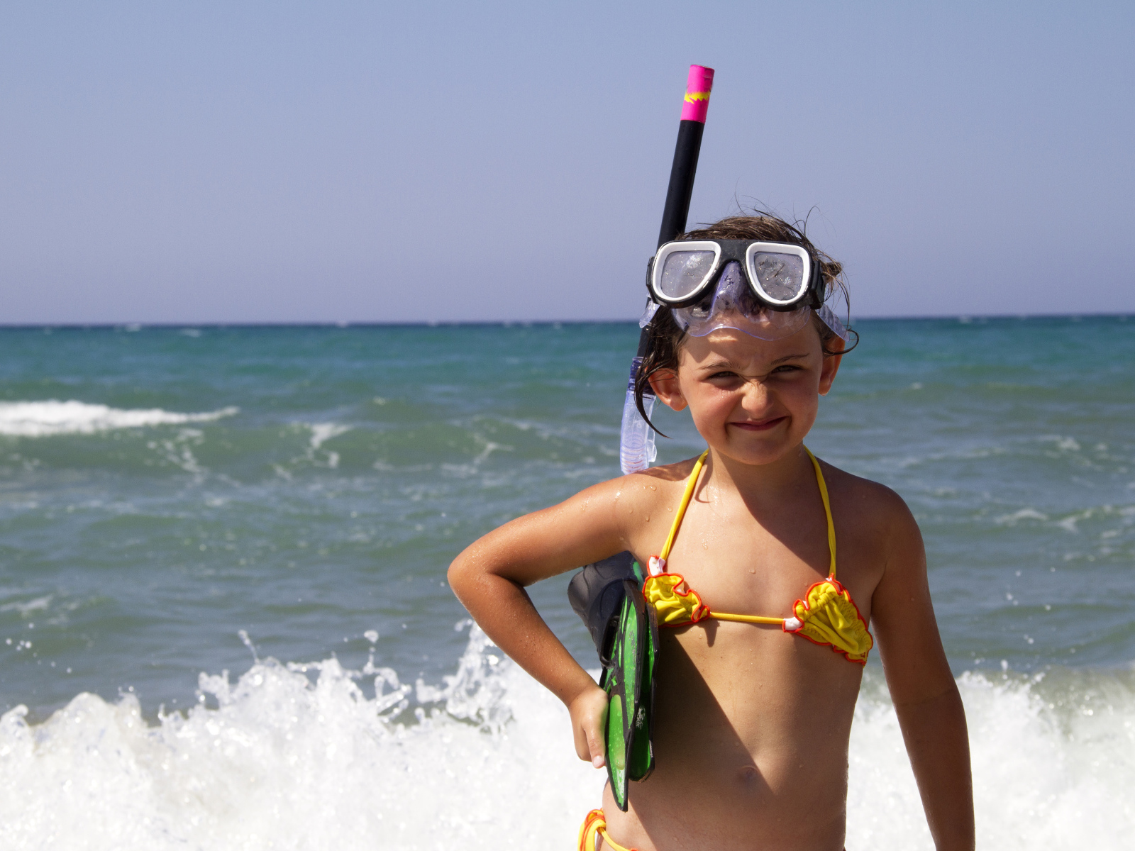 Маленькая девочка в очках и с ластами на море