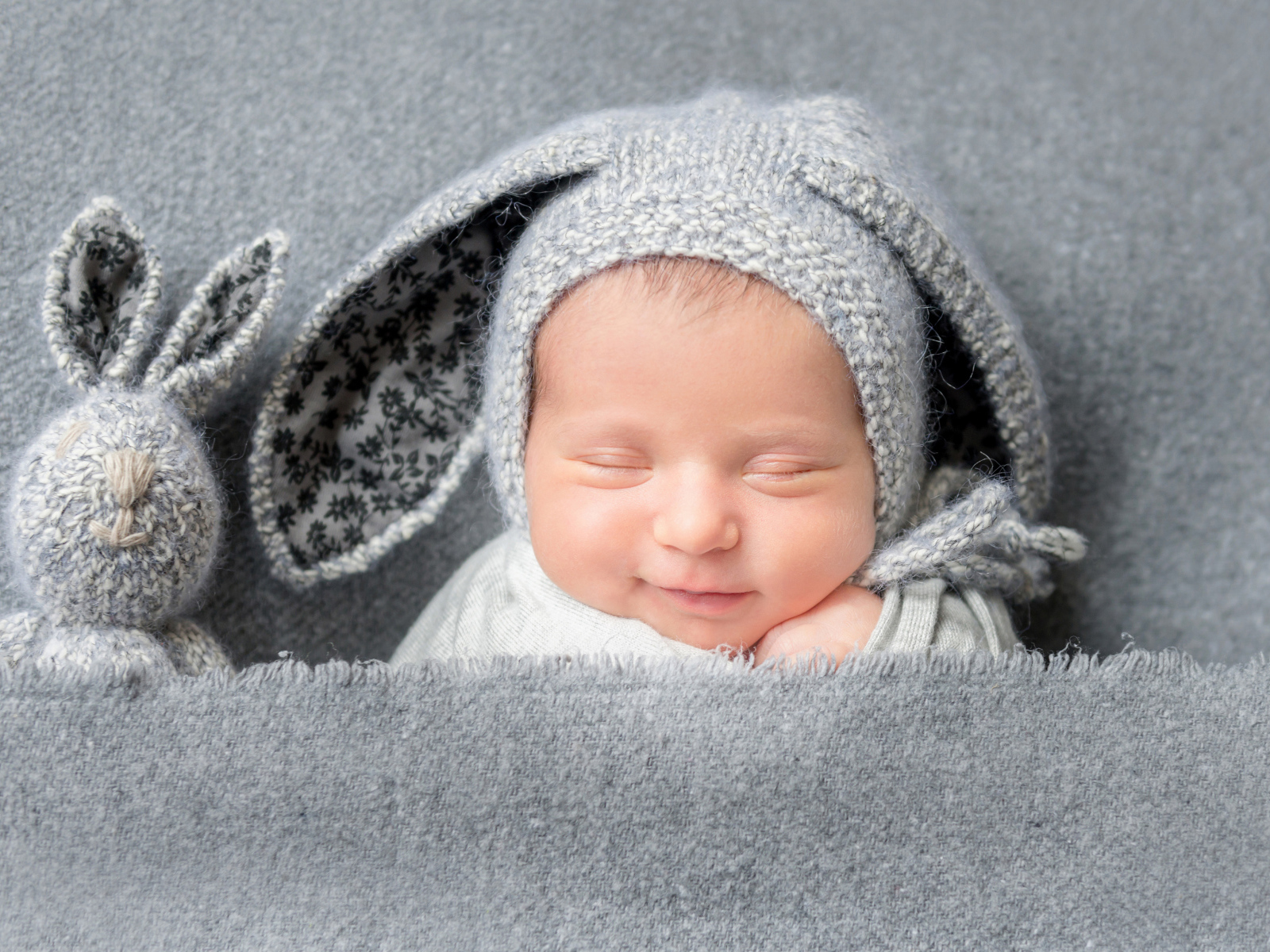 Маленький грудной ребенок в серой шапке с ушками