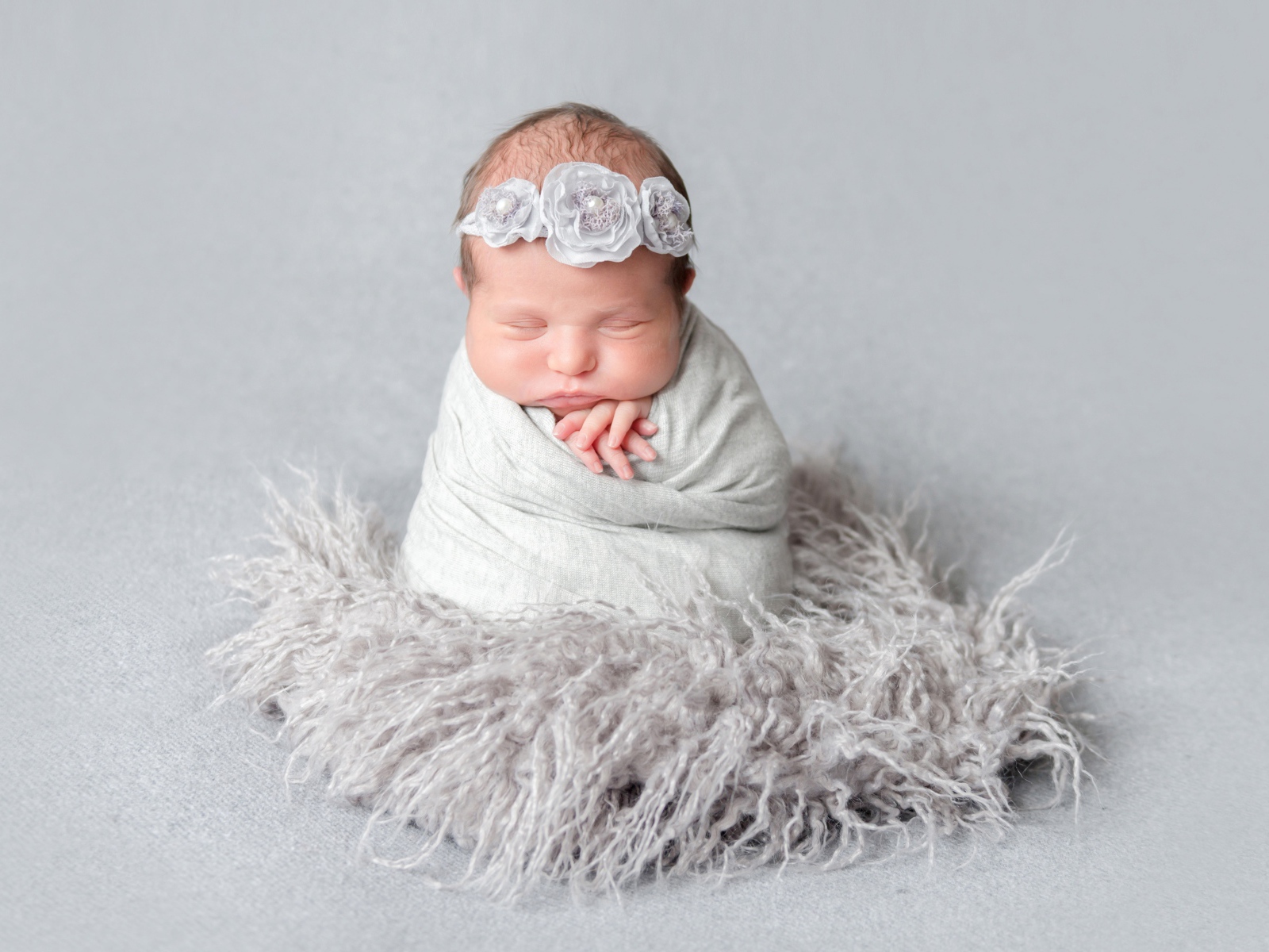 Маленький спящий младенец на сером фоне