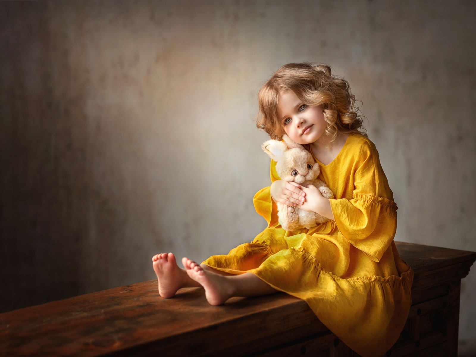 Красивая маленькая девочка в желтом платье с игрушкой