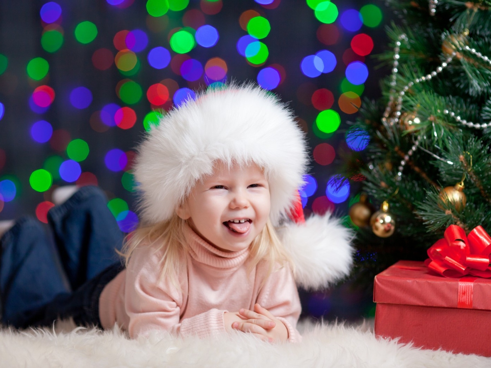 Смешная девочка в новогодней шапке у елки