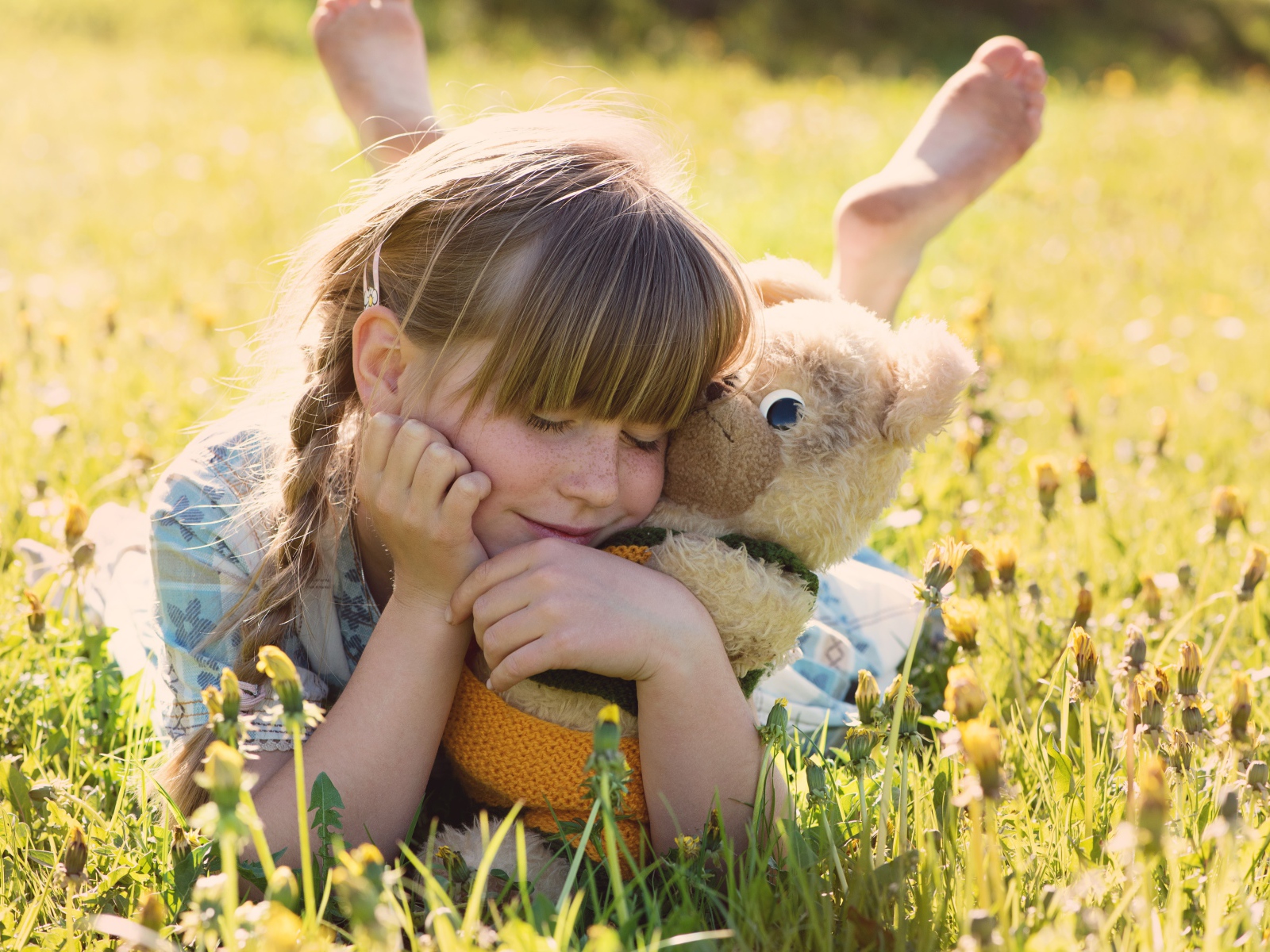 Девочка лежит на траве с игрушкой