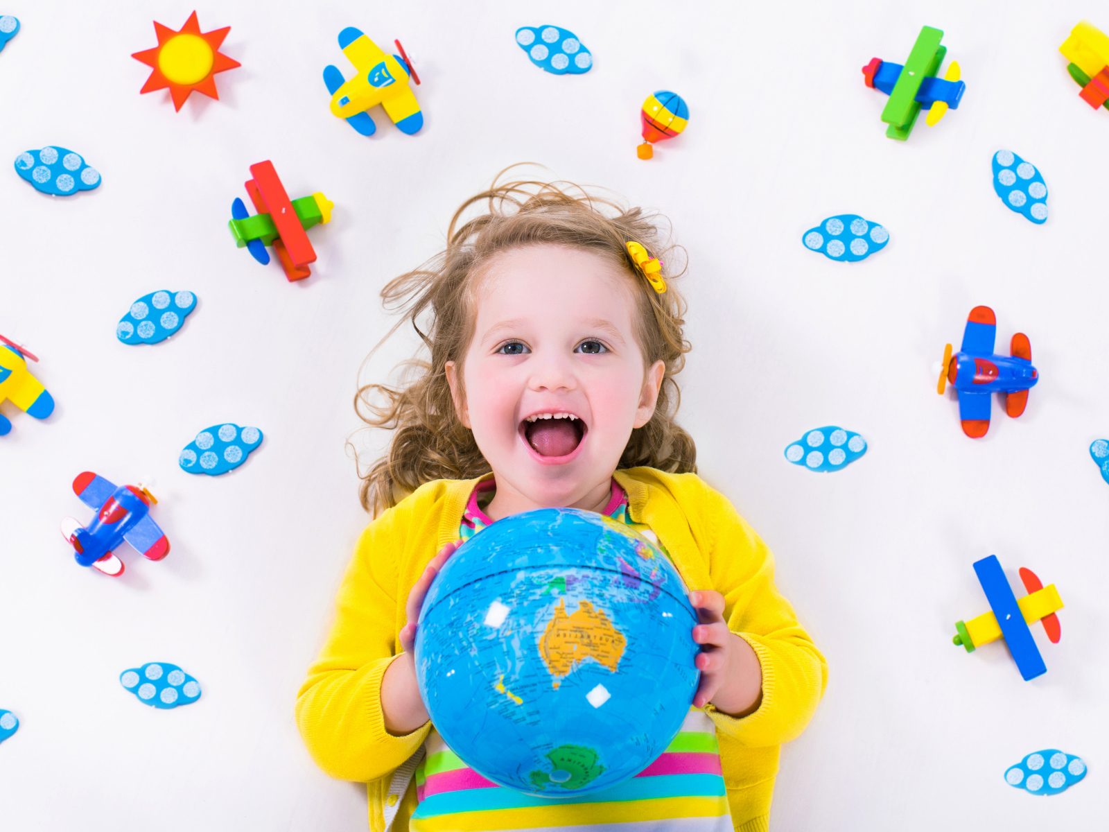 Маленькая веселая девочка с глобусом в руках 