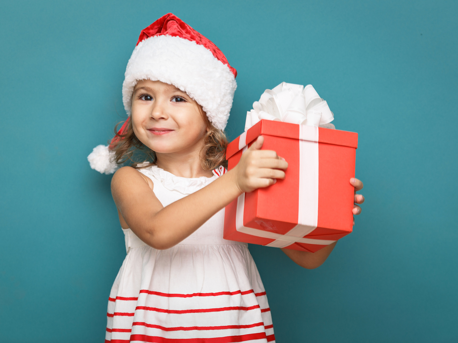 Маленькая девочка в новогоднем костюме с подарком на голубом фоне
