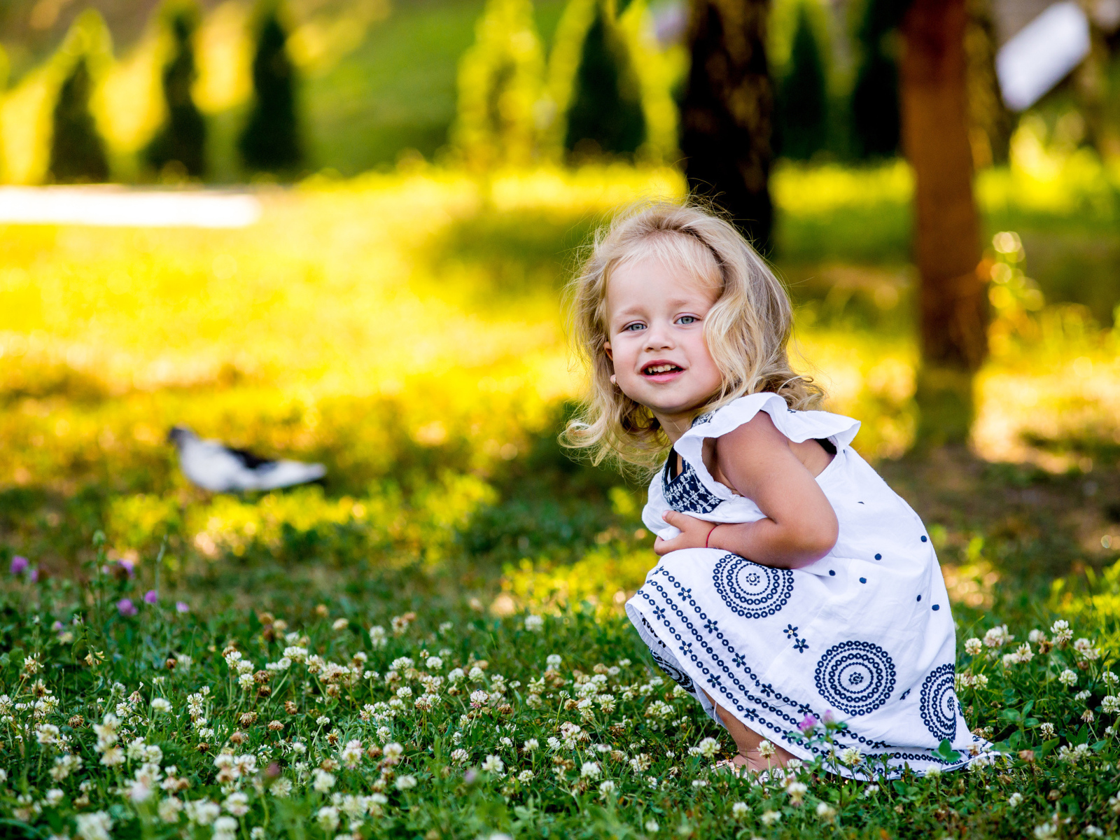 Маленькая девочка в красивом платье сидит на зеленой траве