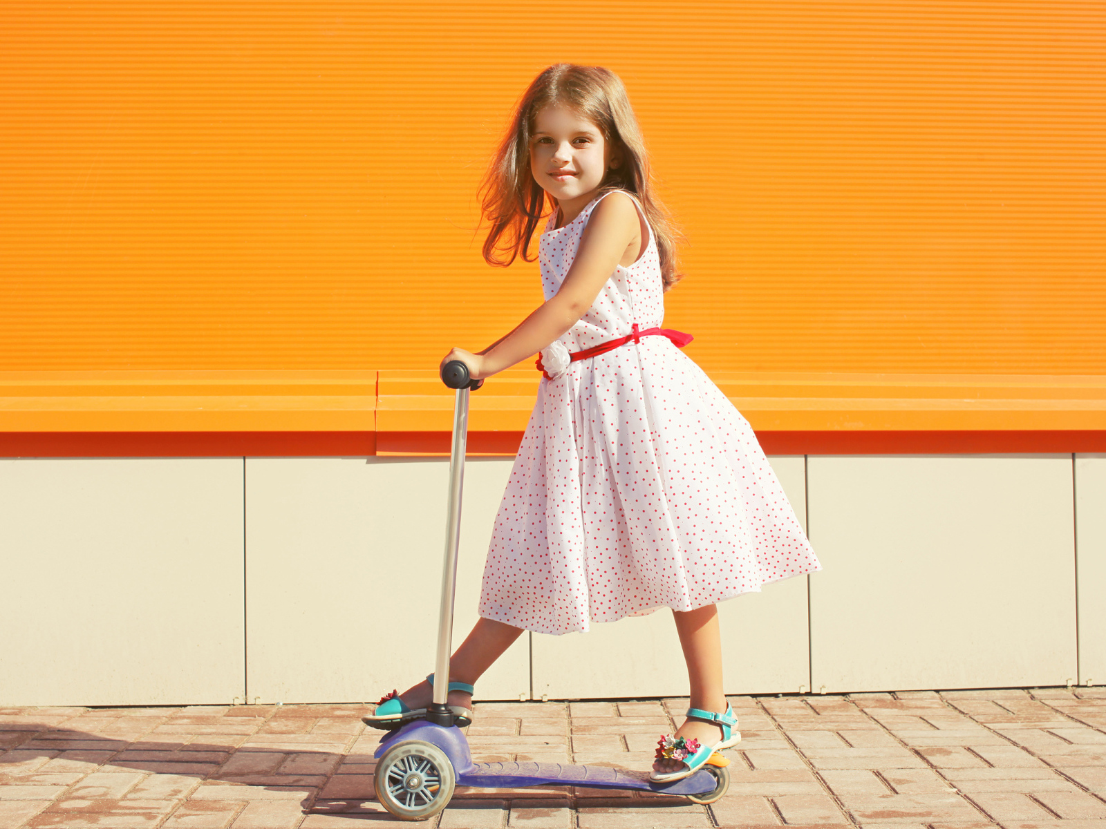 Маленькая девочка в платье на самокате 