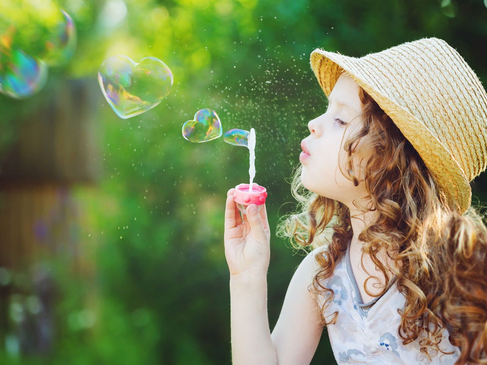 Маленькая девочка в шляпе с мыльными пузырями