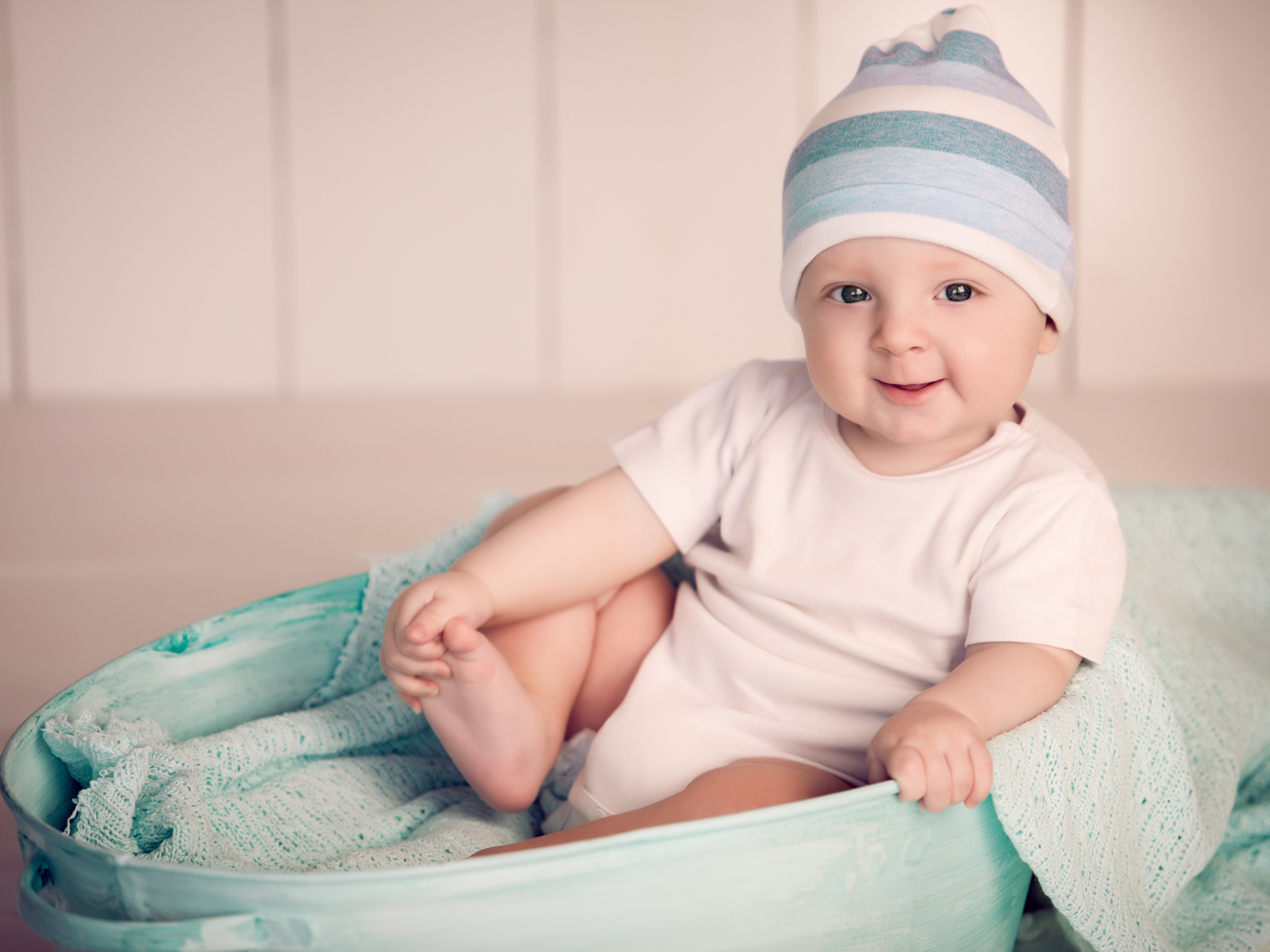 Маленький улыбающийся ребенок сидит в железном тазике