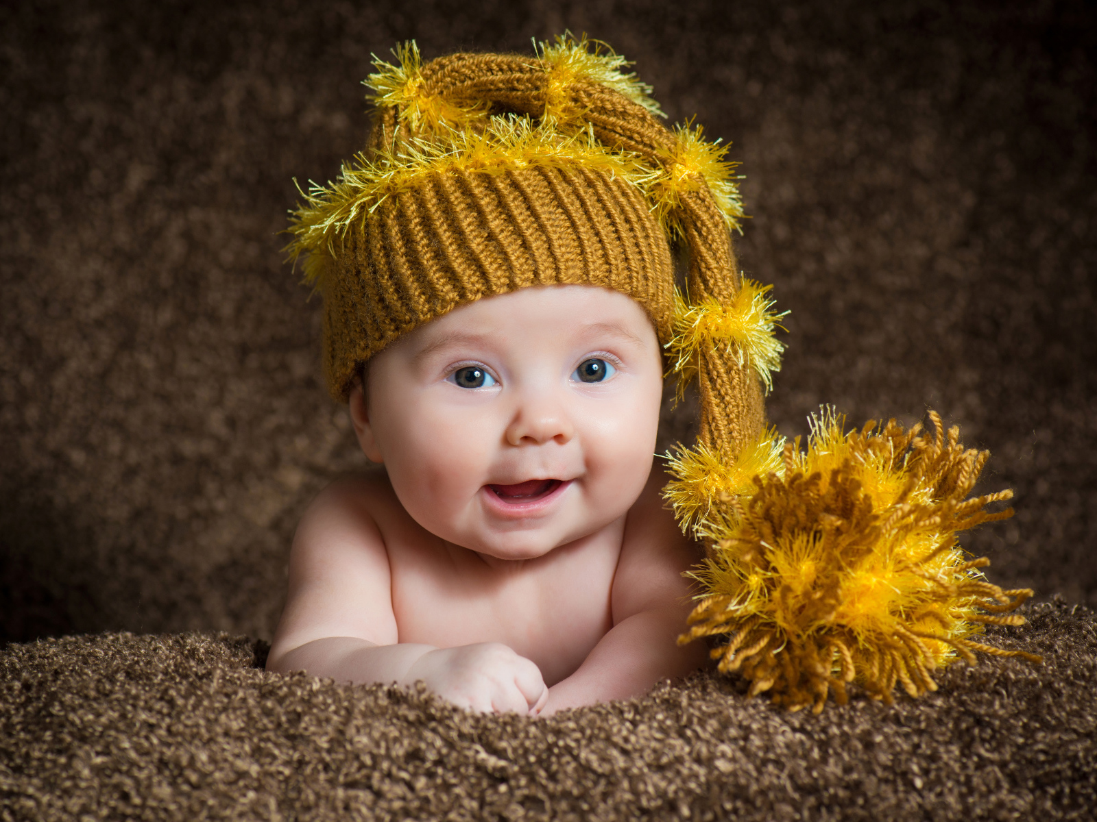 Улыбающийся малыш в красивой вязанной шапке 