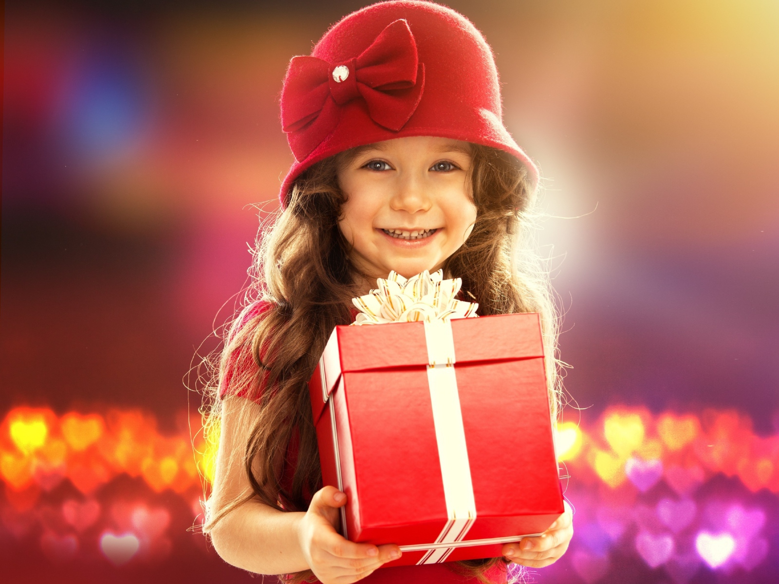 Улыбающаяся голубоглазая девочка с большим подарком в руках